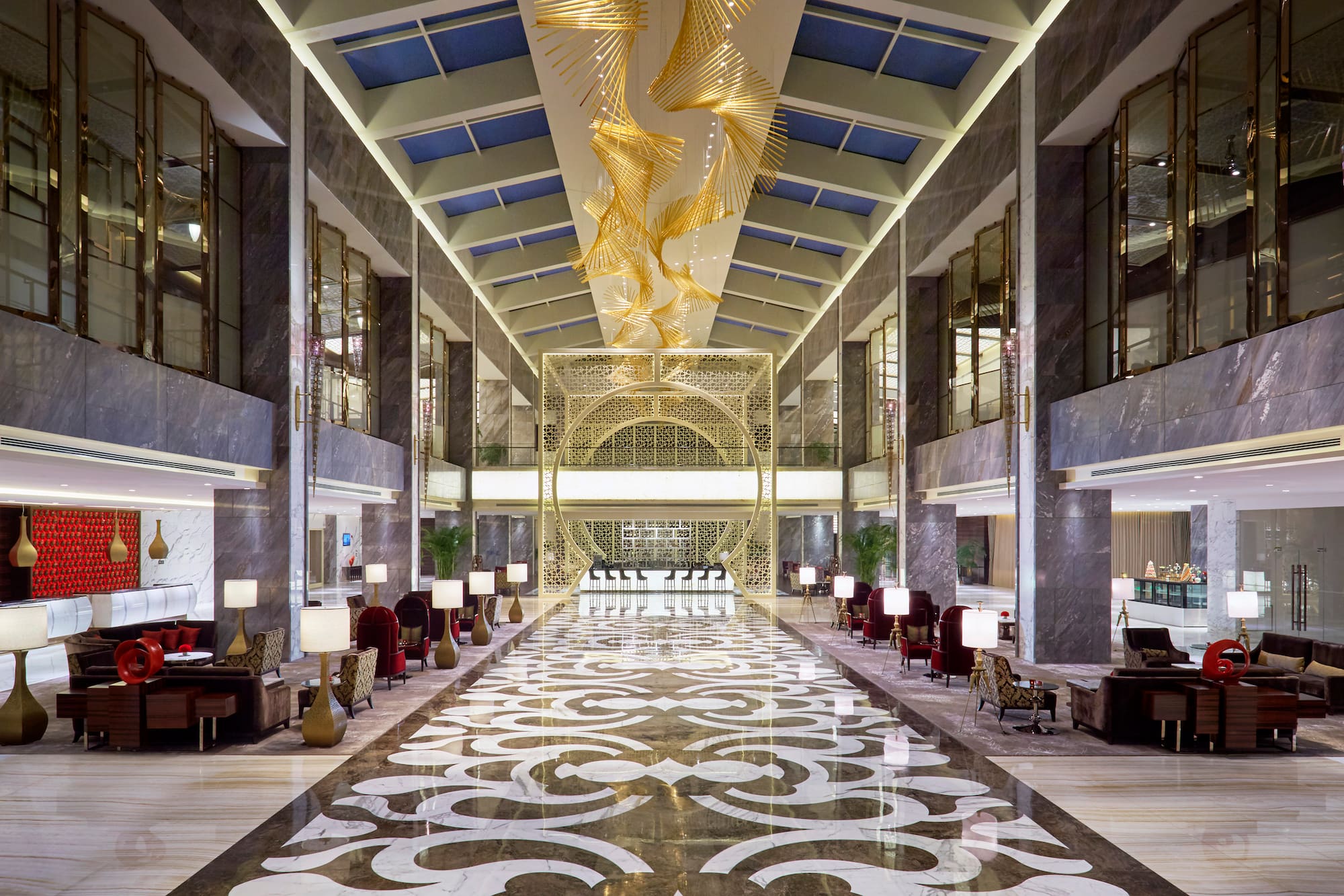 Grand hotel lobby: gold chandelier, patterned marble floor, elegant seating.