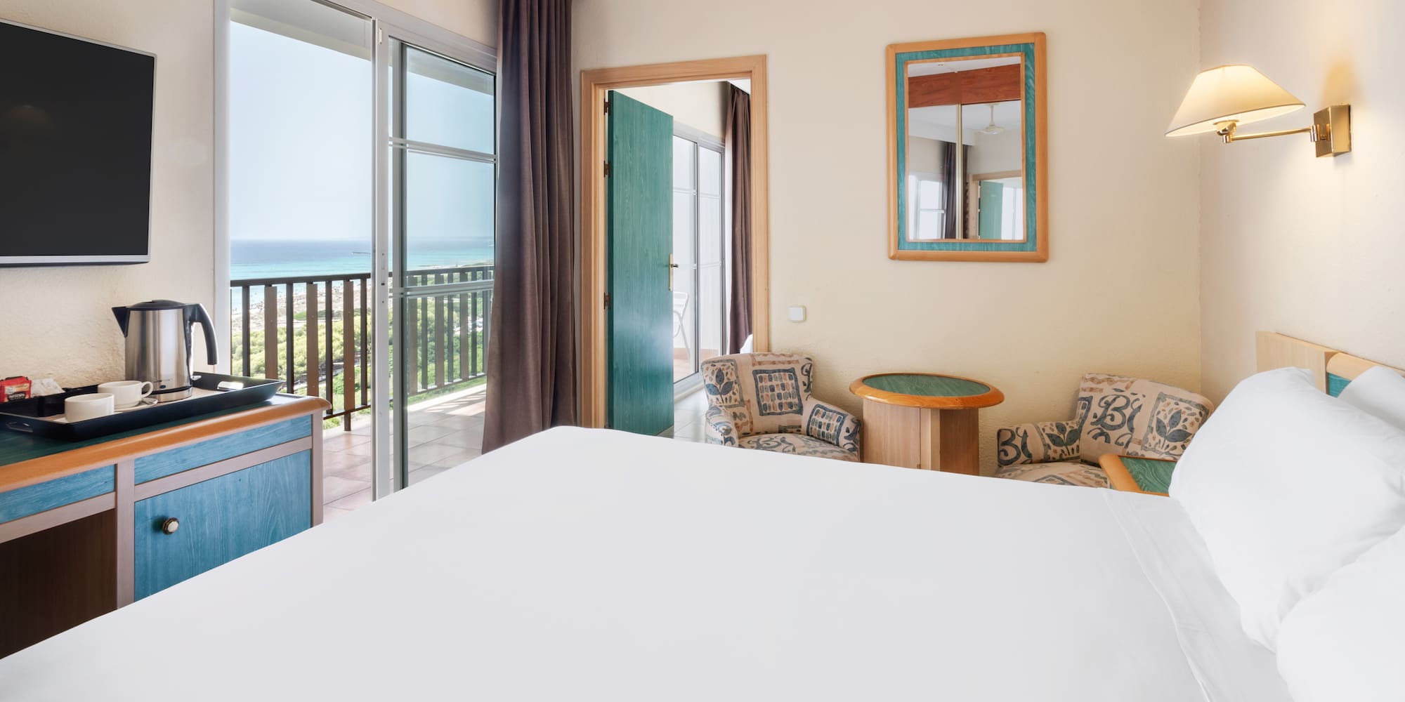 a room with a bed and a balcony overlooking the ocean