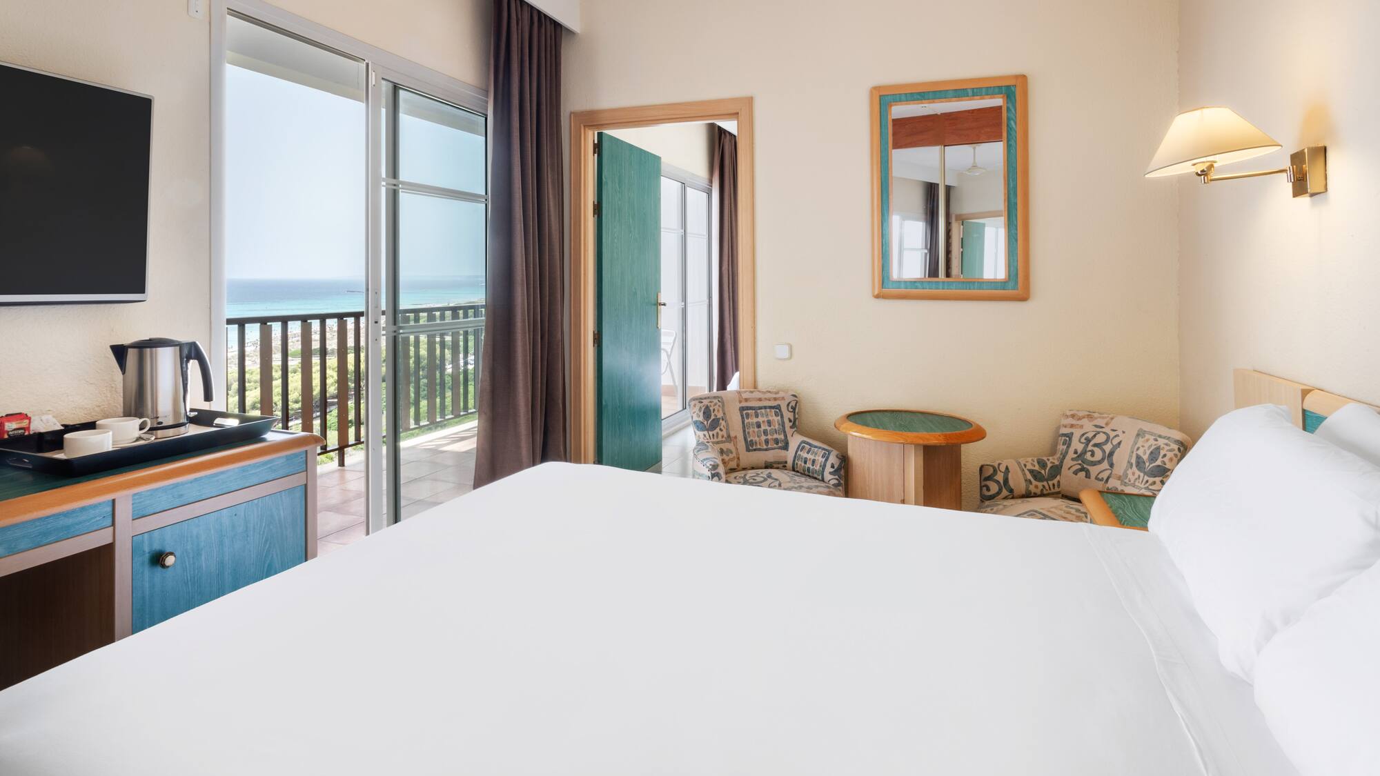 a room with a bed and a balcony overlooking the ocean