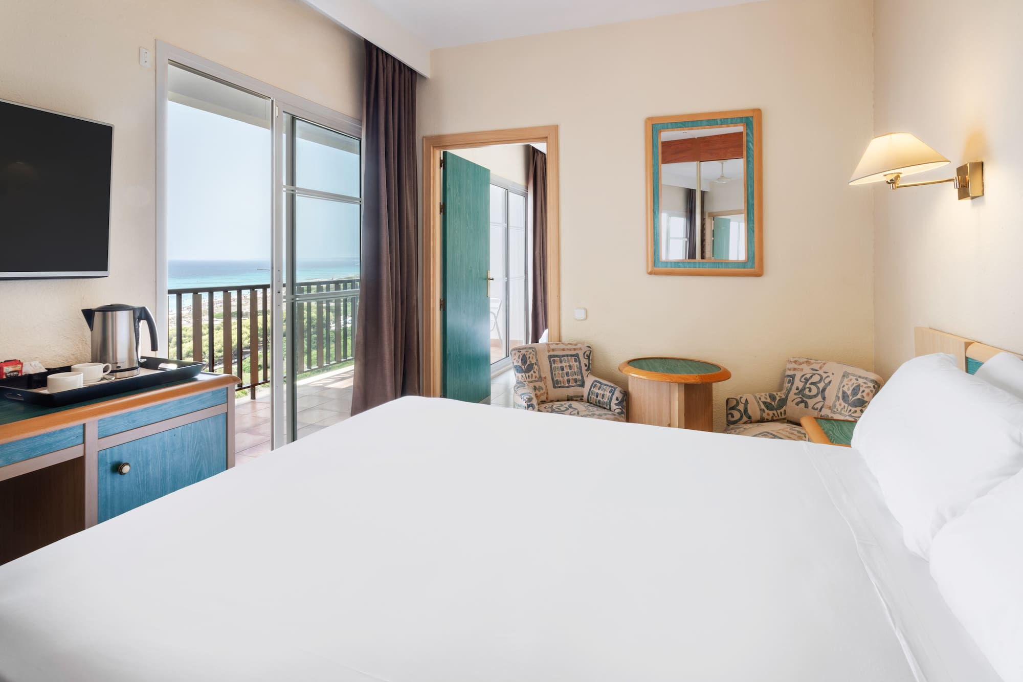 a room with a bed and a balcony overlooking the ocean