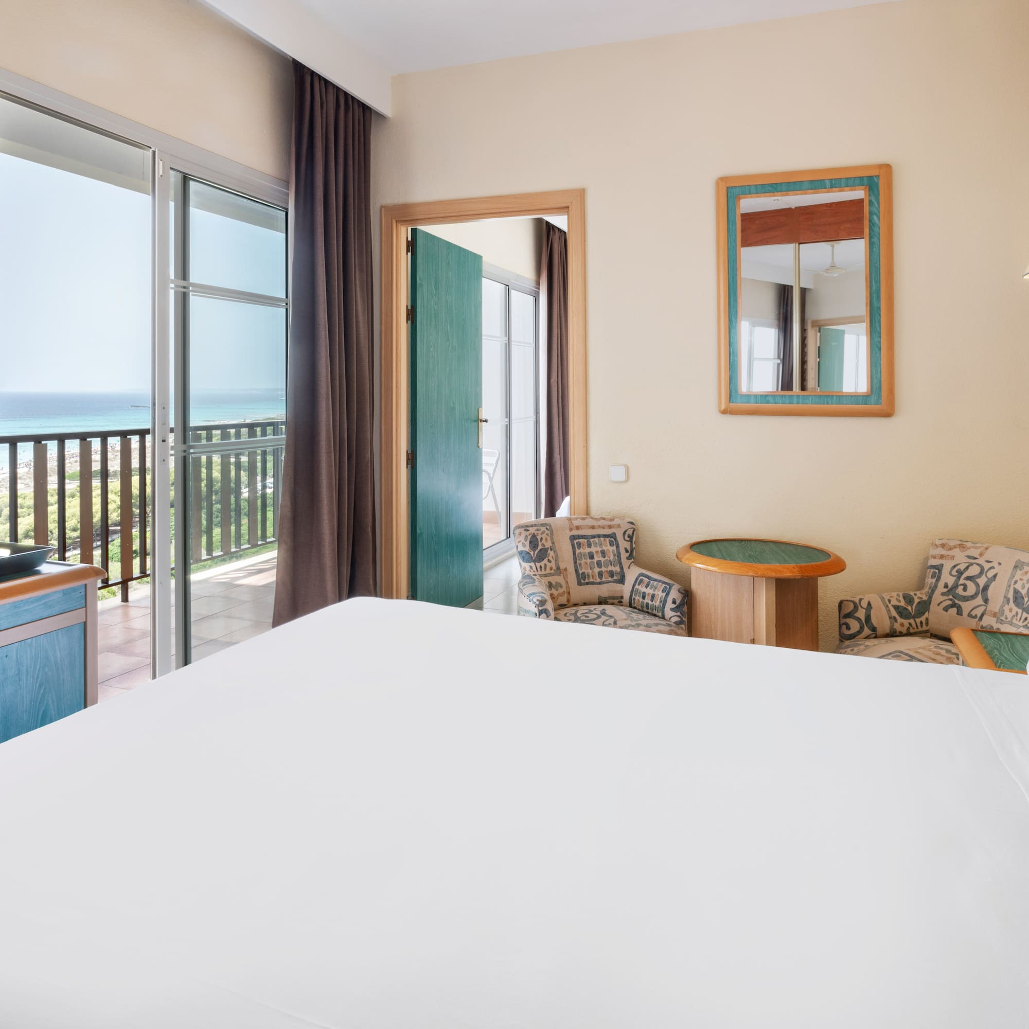 a room with a bed and a balcony overlooking the ocean