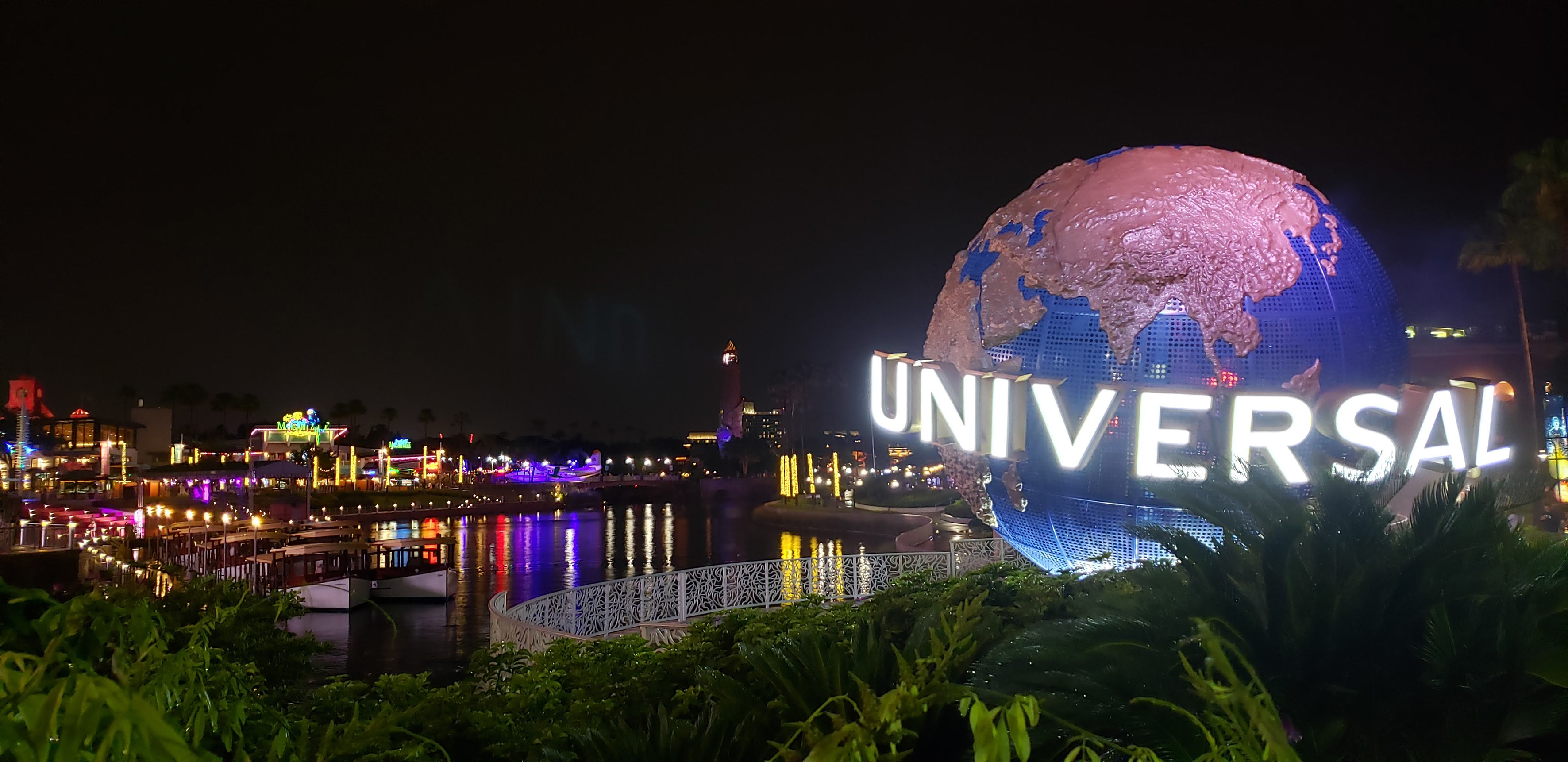 Universal Orlando Globe sign glowing at night, CityWalk lights on water. - Universal Epic Universe™ - Meliá Orlando Celebration, Orlando