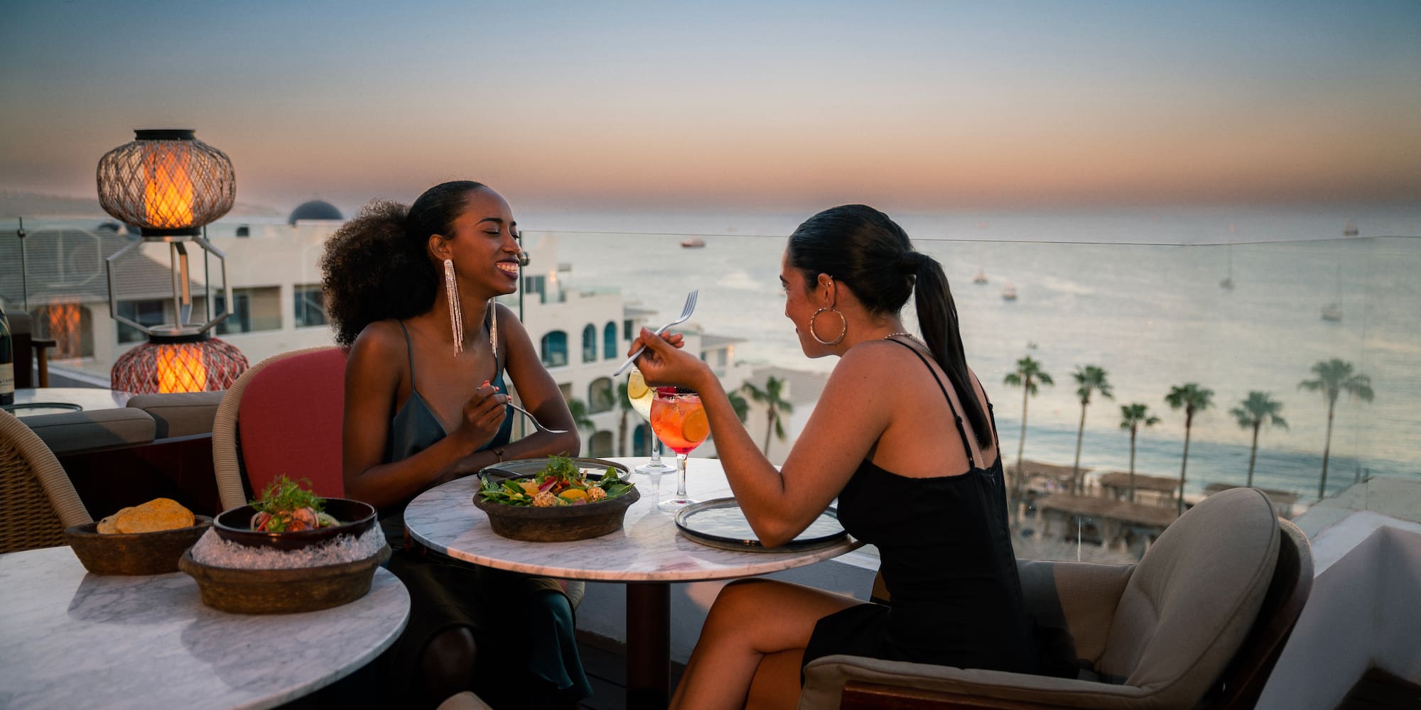 a group of women sitting at a table with food and drinks