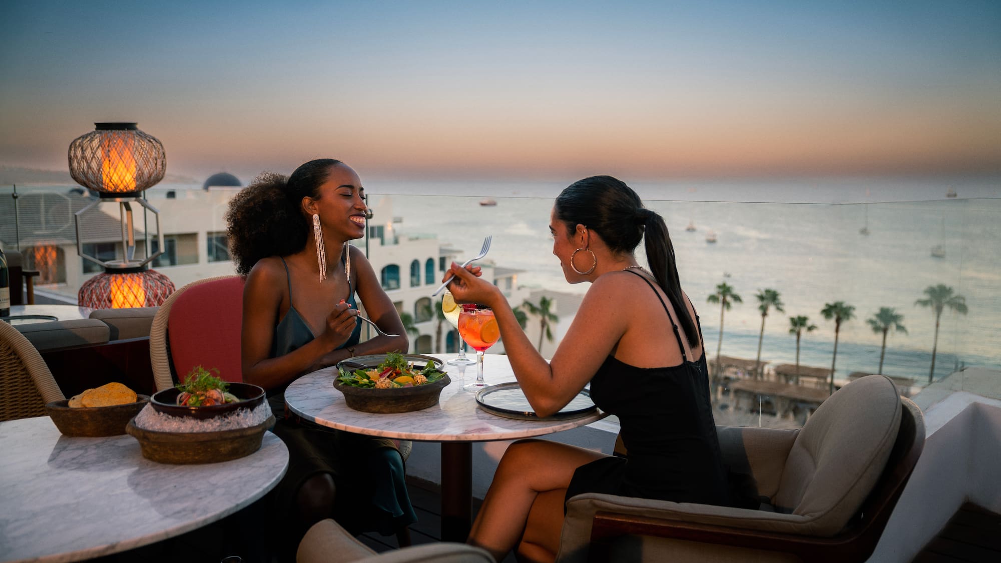 a group of women sitting at a table with food and drinks
