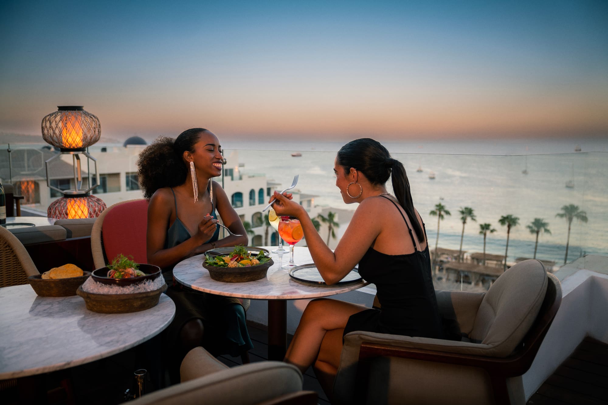a group of women sitting at a table with food and drinks