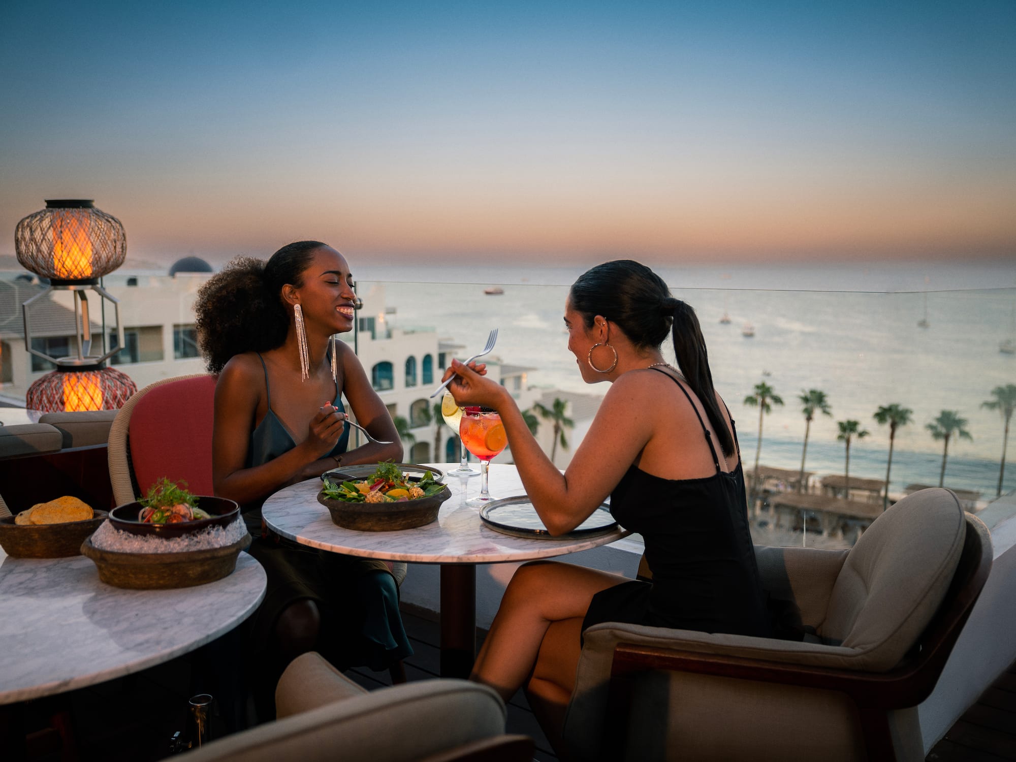 a group of women sitting at a table with food and drinks