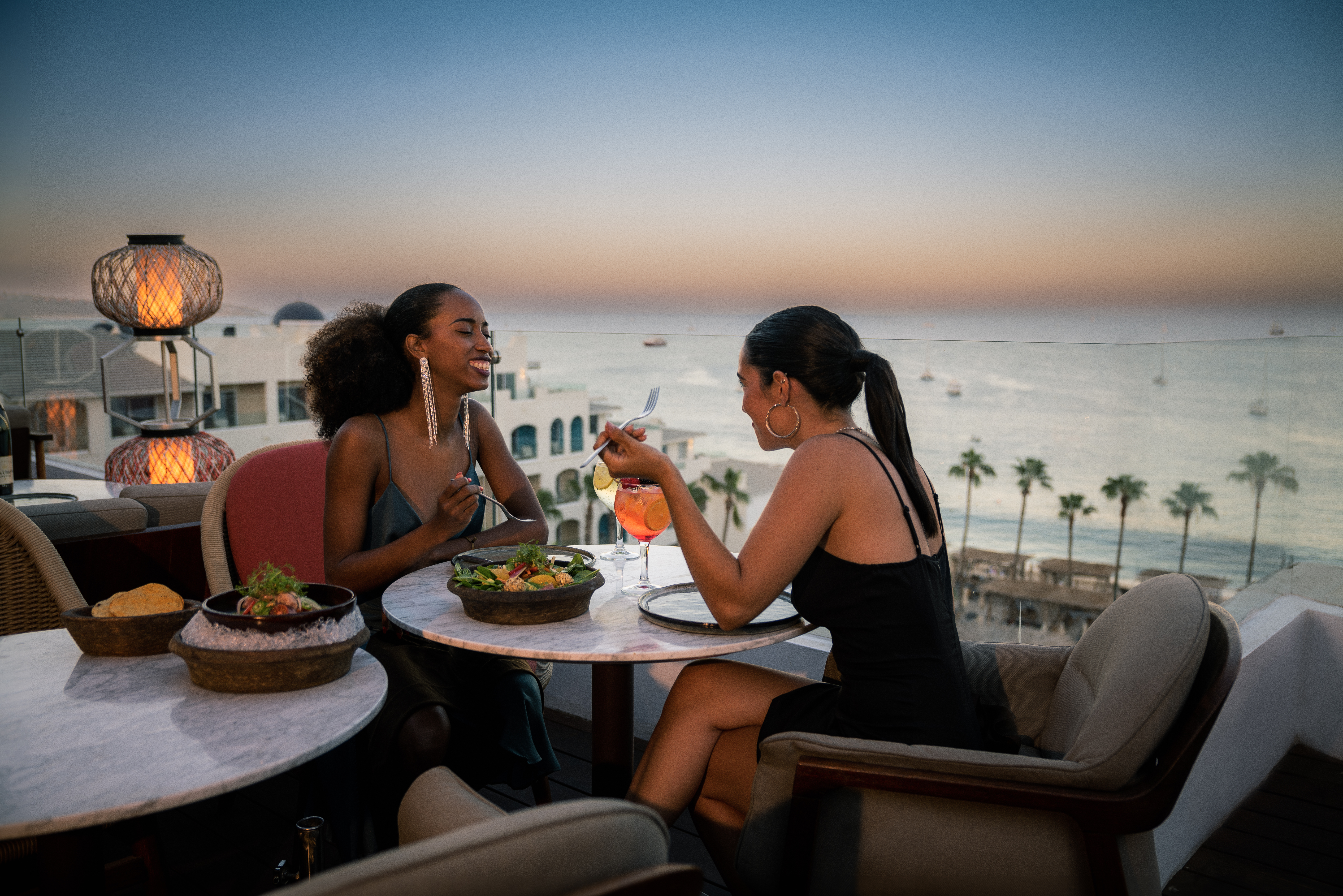 a group of women sitting at a table with food and drinks