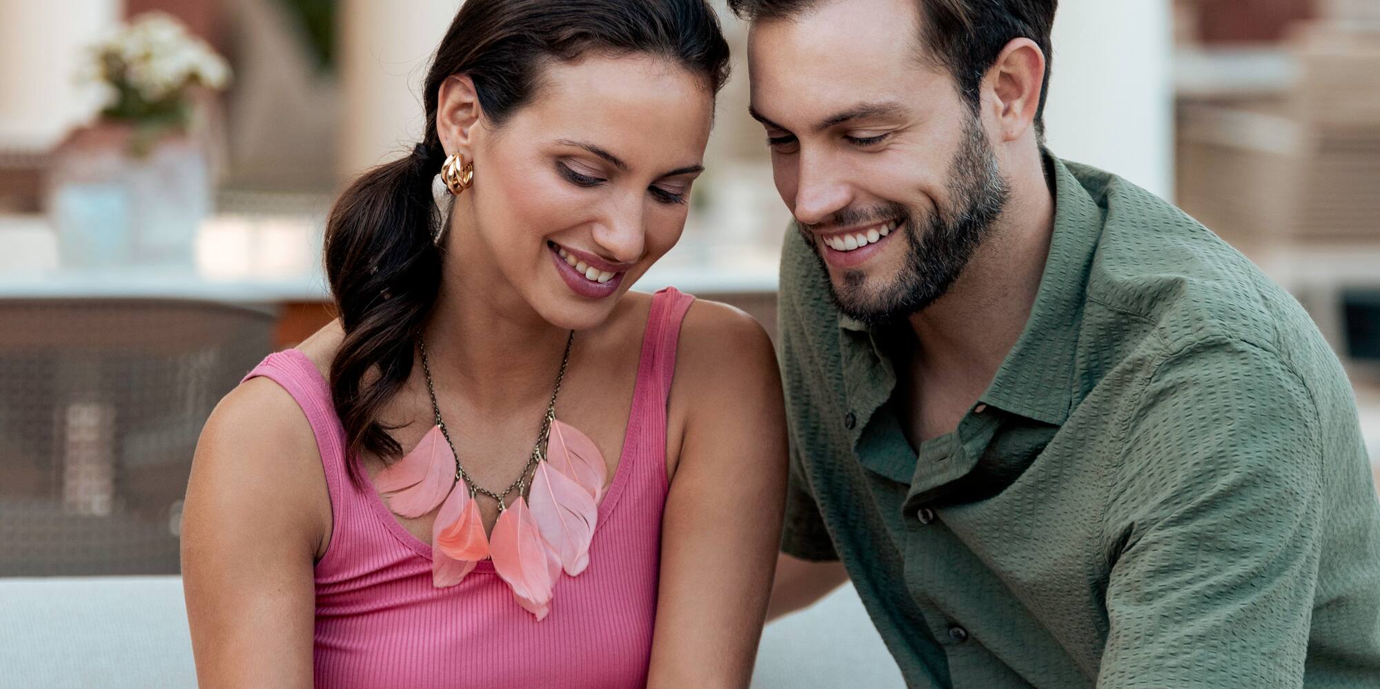 a man and woman sitting on a couch looking at a phone