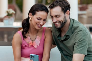 a man and woman sitting on a couch looking at a phone
