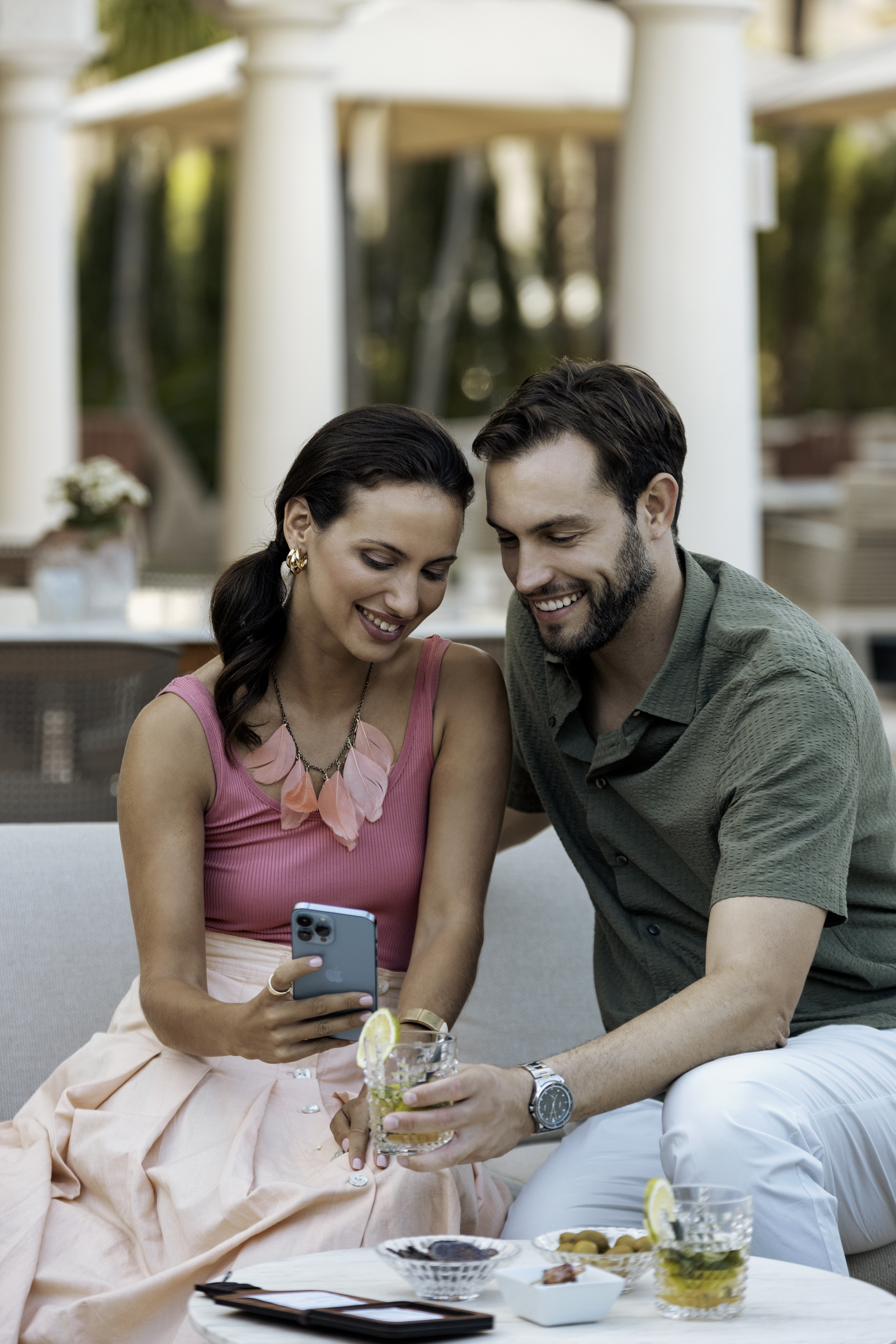 a man and woman sitting on a couch looking at a phone