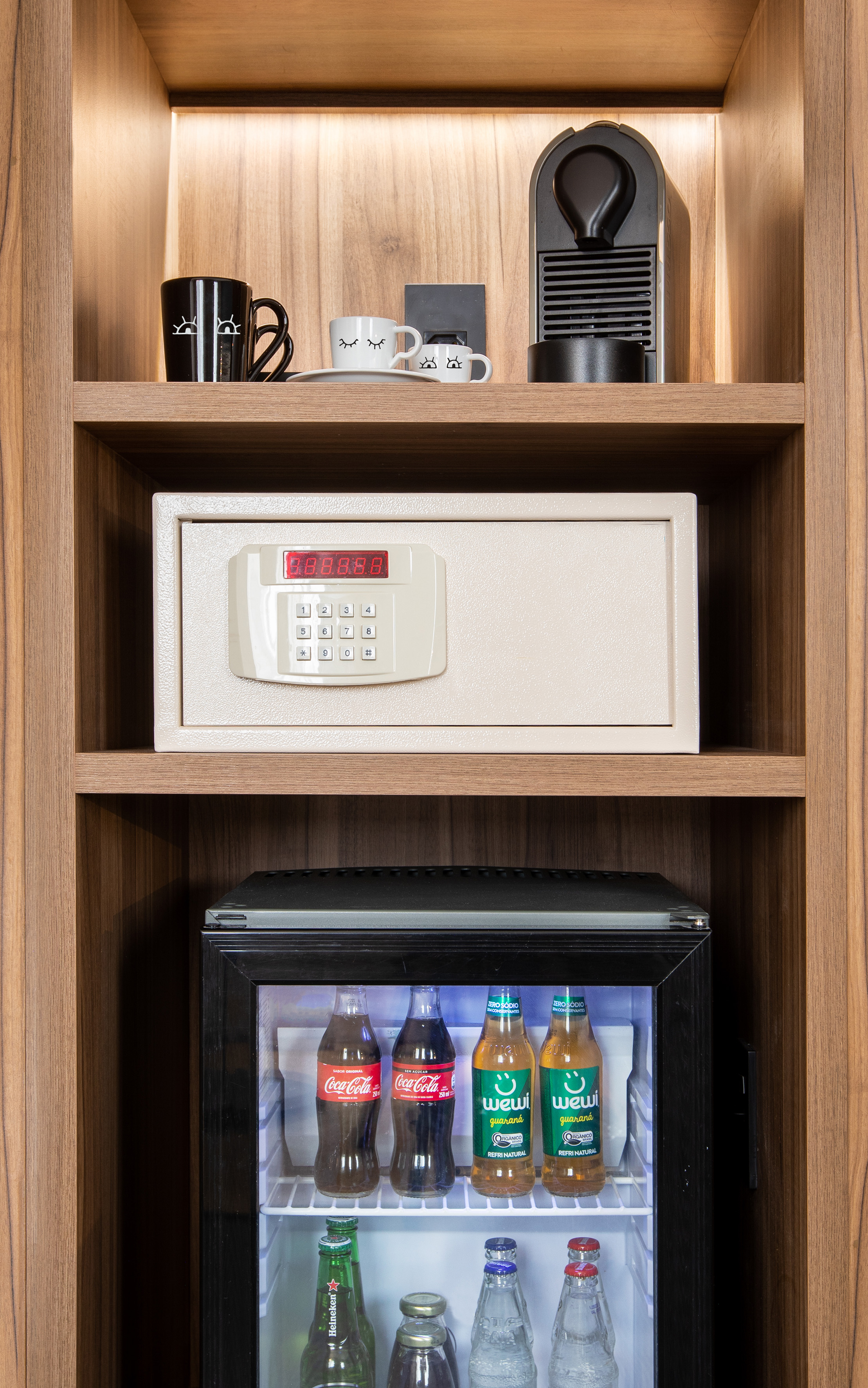 Hotel room minibar, electronic safe, and Nespresso machine in wood shelving.