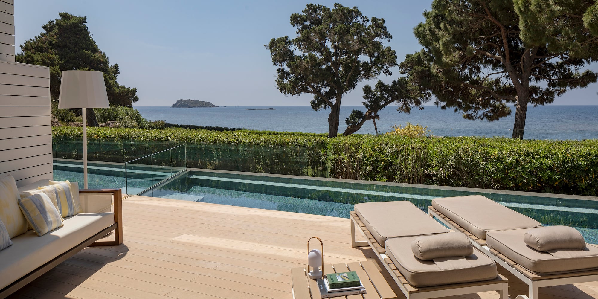 a deck with chairs and a pool overlooking the ocean