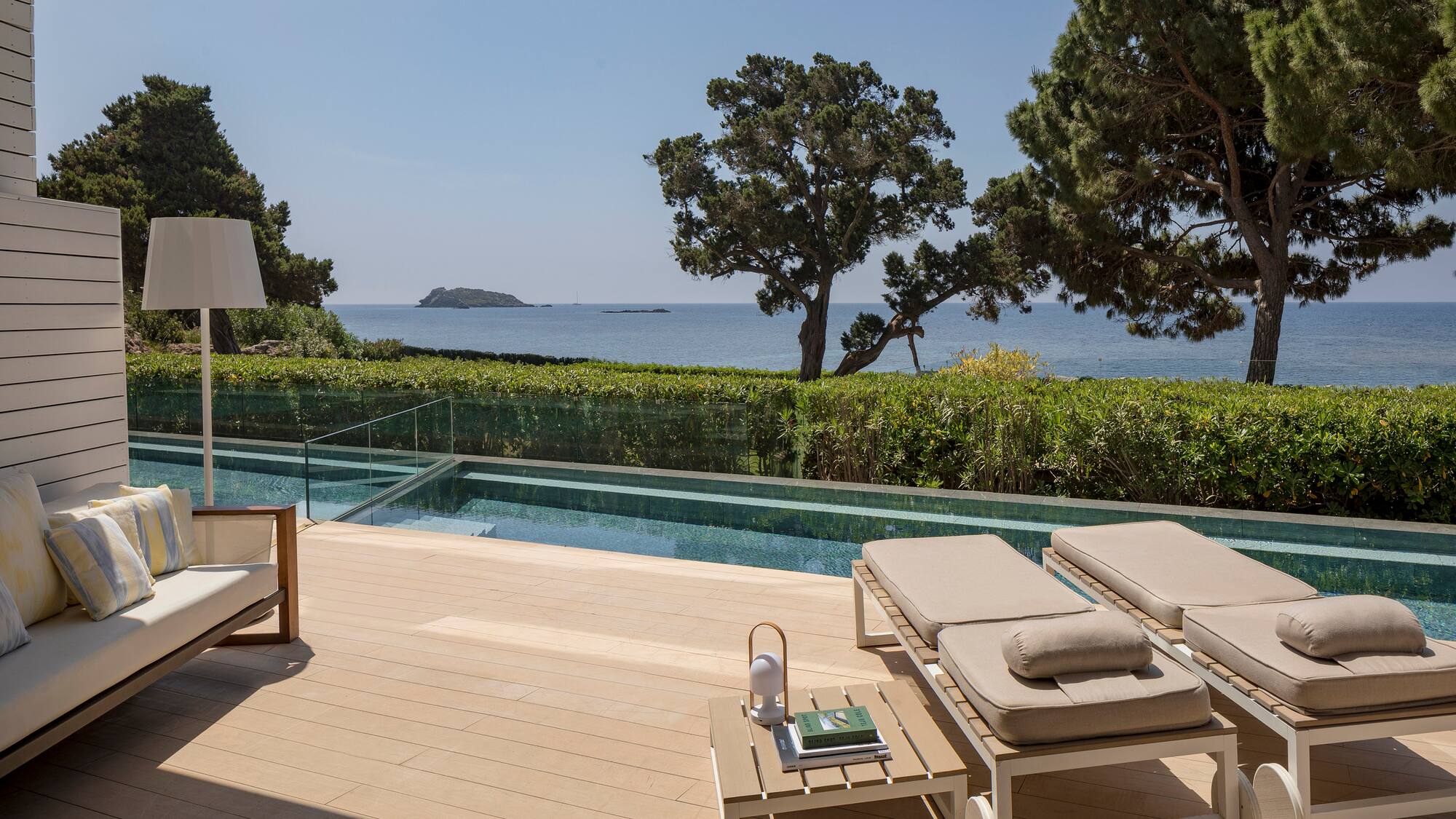 a deck with chairs and a pool overlooking the ocean