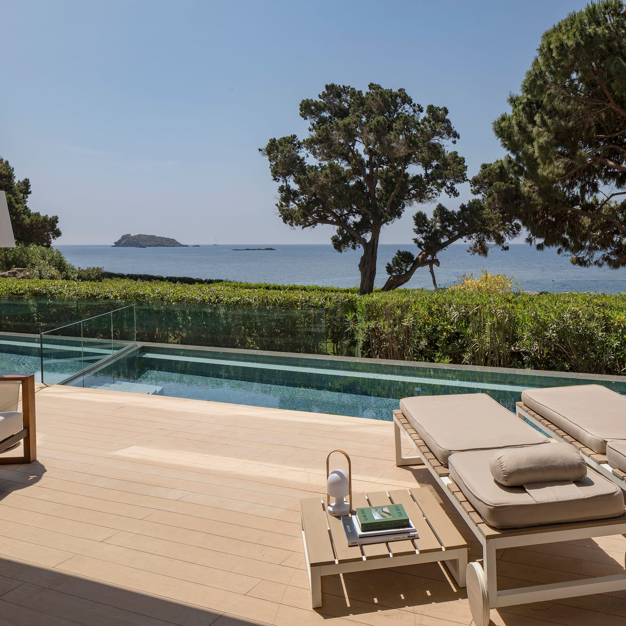 a deck with chairs and a pool overlooking the ocean