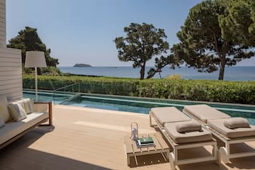 a deck with chairs and a pool overlooking the ocean