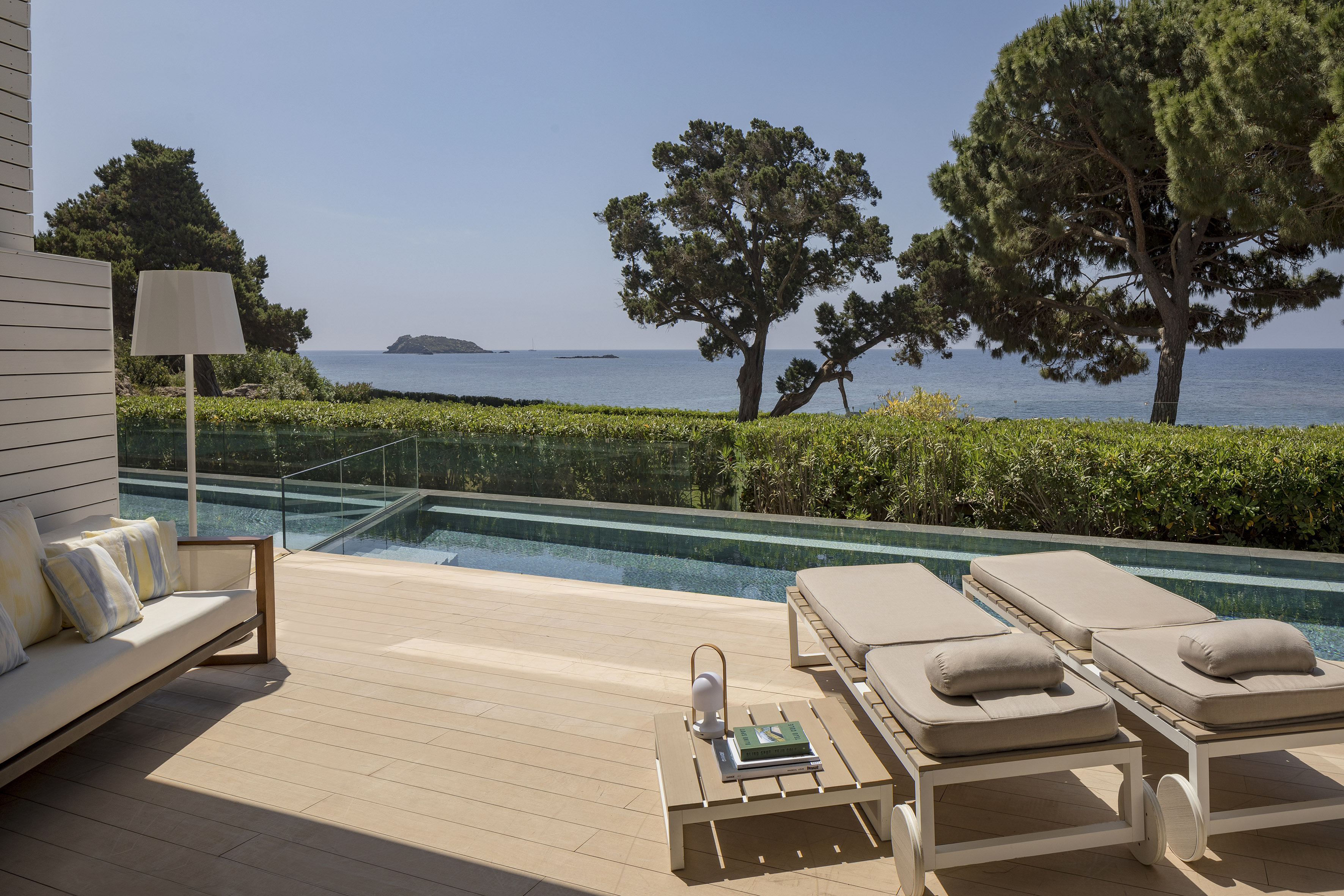 a deck with chairs and a pool overlooking the ocean