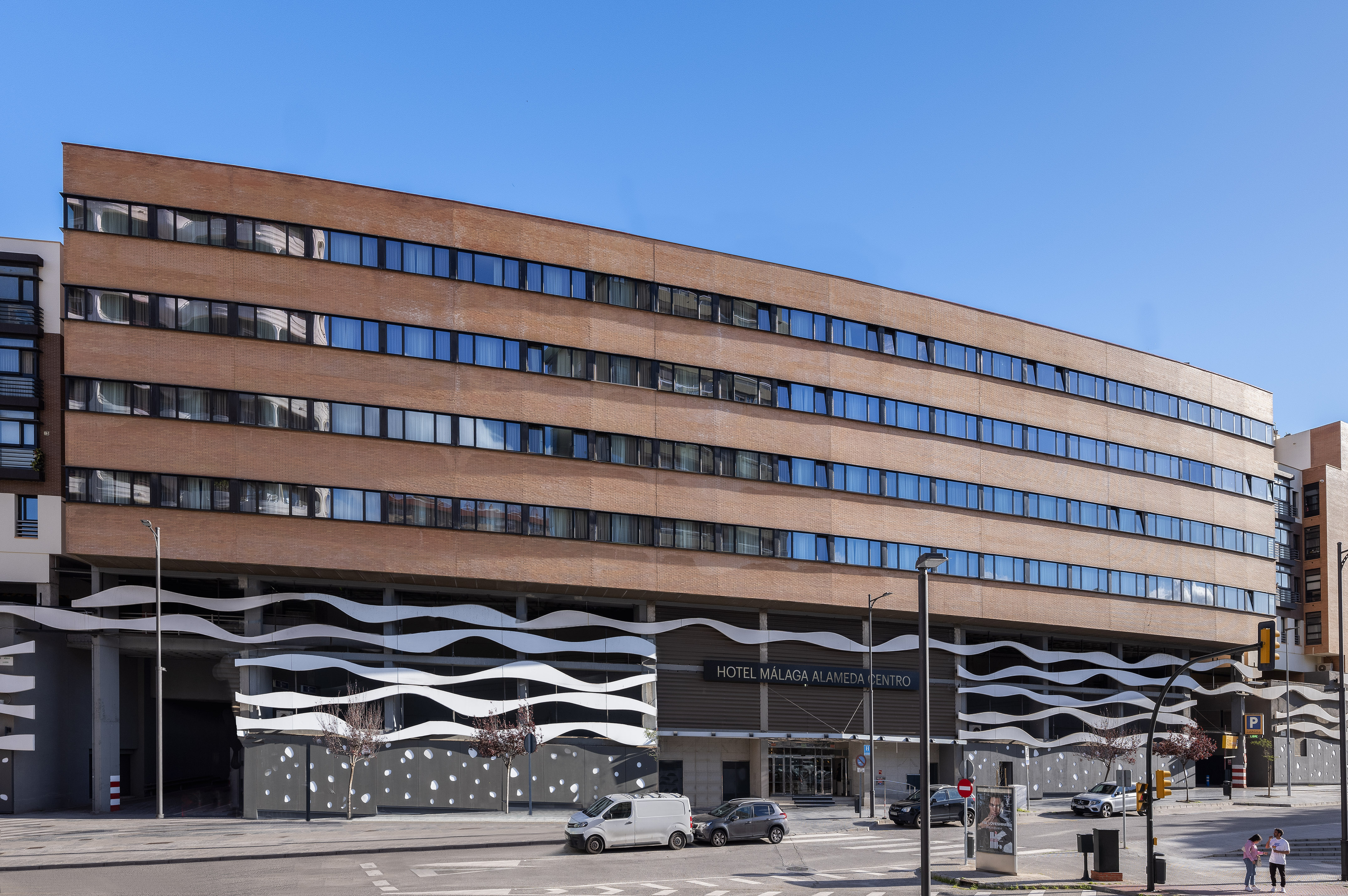 Hotel Málaga Alameda Centro building with brick facade and modern wavy lower section.