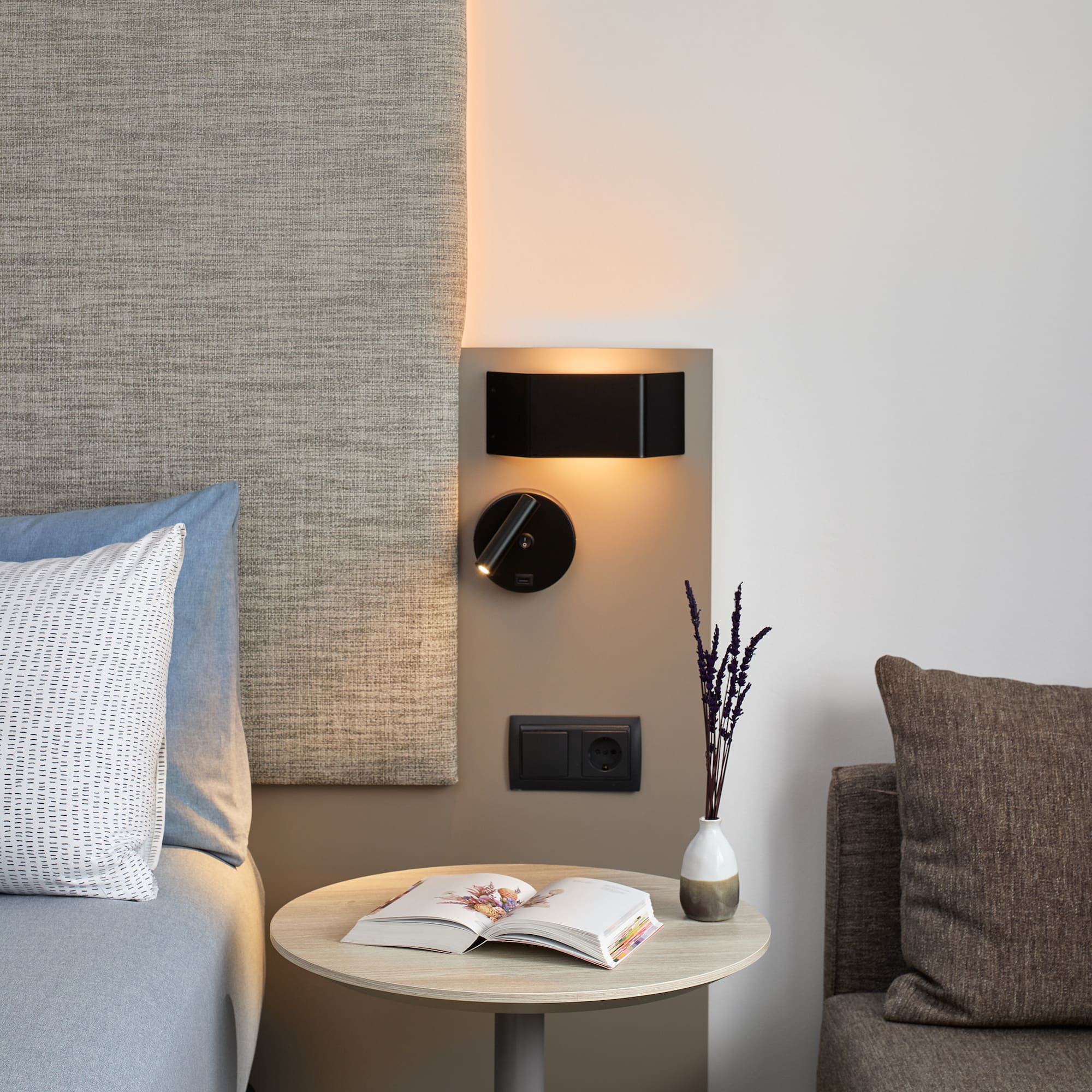 a table with a book and a lamp on the wall