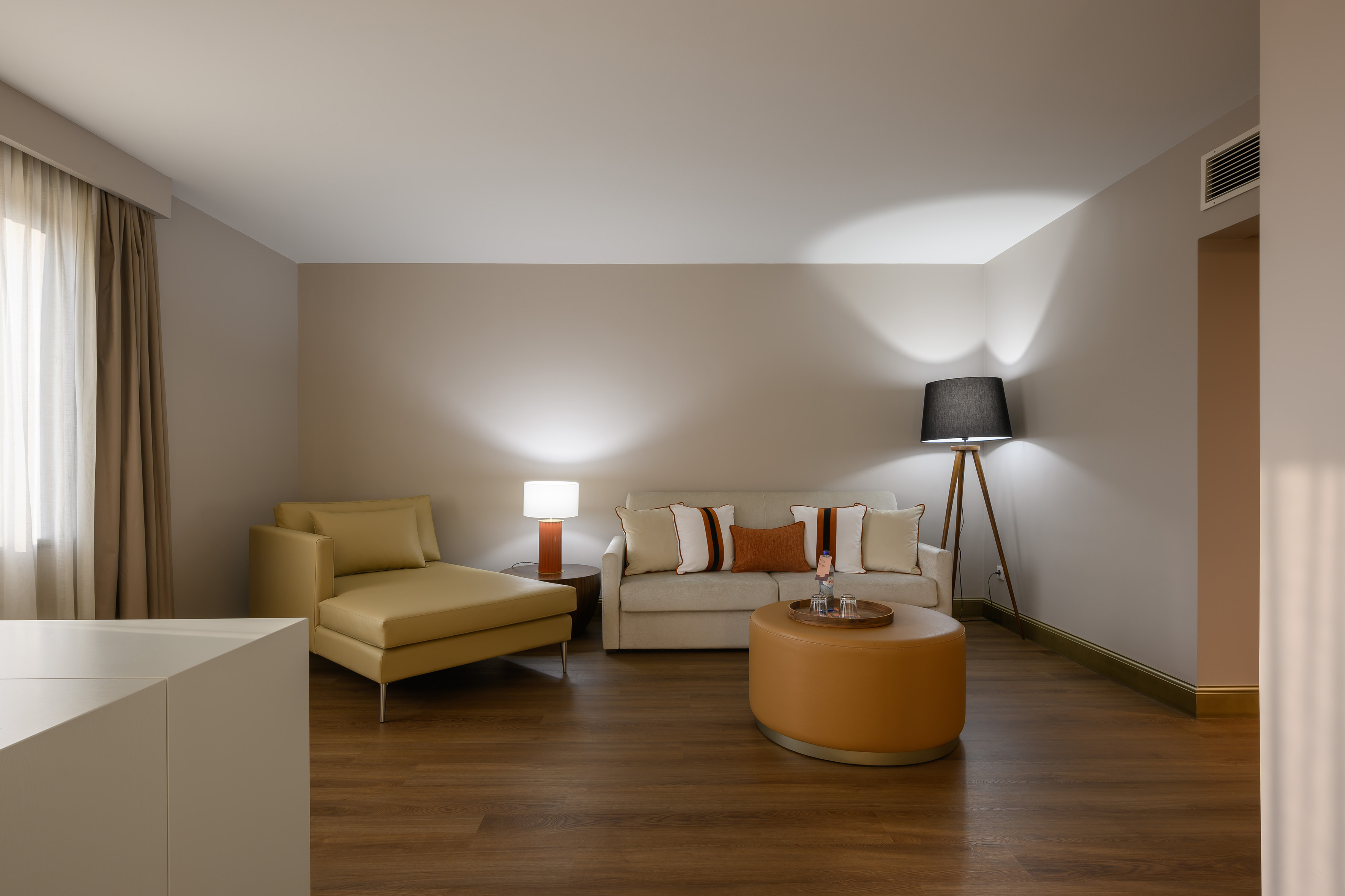 Modern living room with a light sofa, tan chaise lounge, and round ottoman.