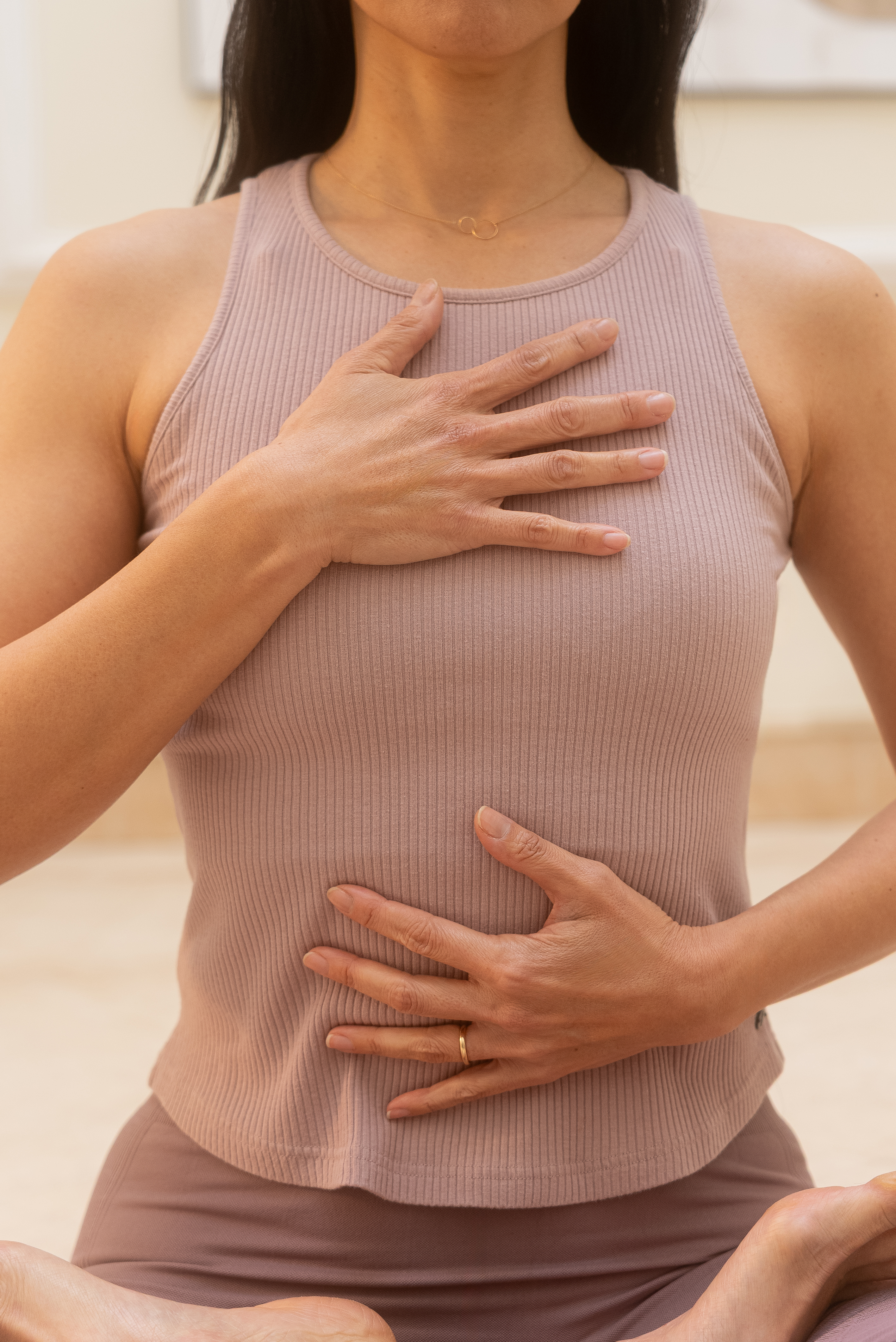 Woman meditating, hands on heart and belly, for mindful breathing.