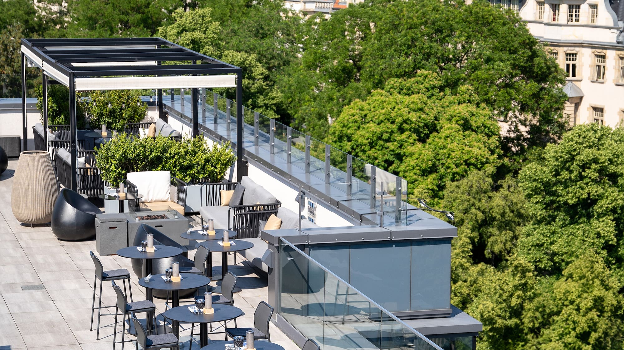 a rooftop patio with tables and chairs and trees