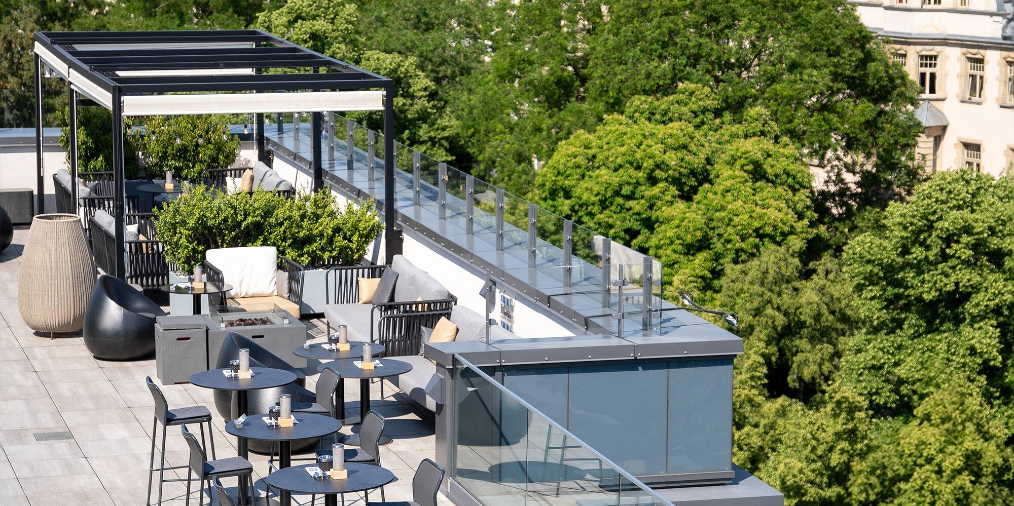 a rooftop patio with tables and chairs and trees