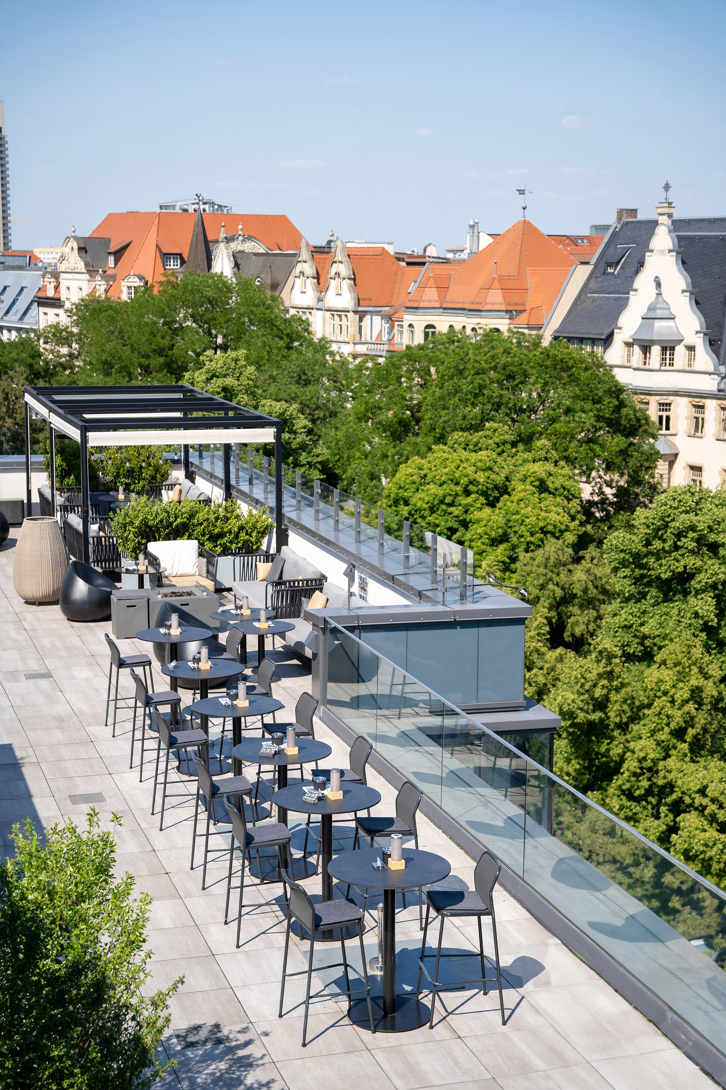a rooftop patio with tables and chairs and trees