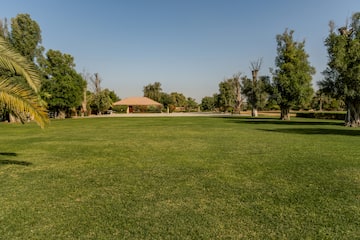 a large grassy area with trees and a building in the background