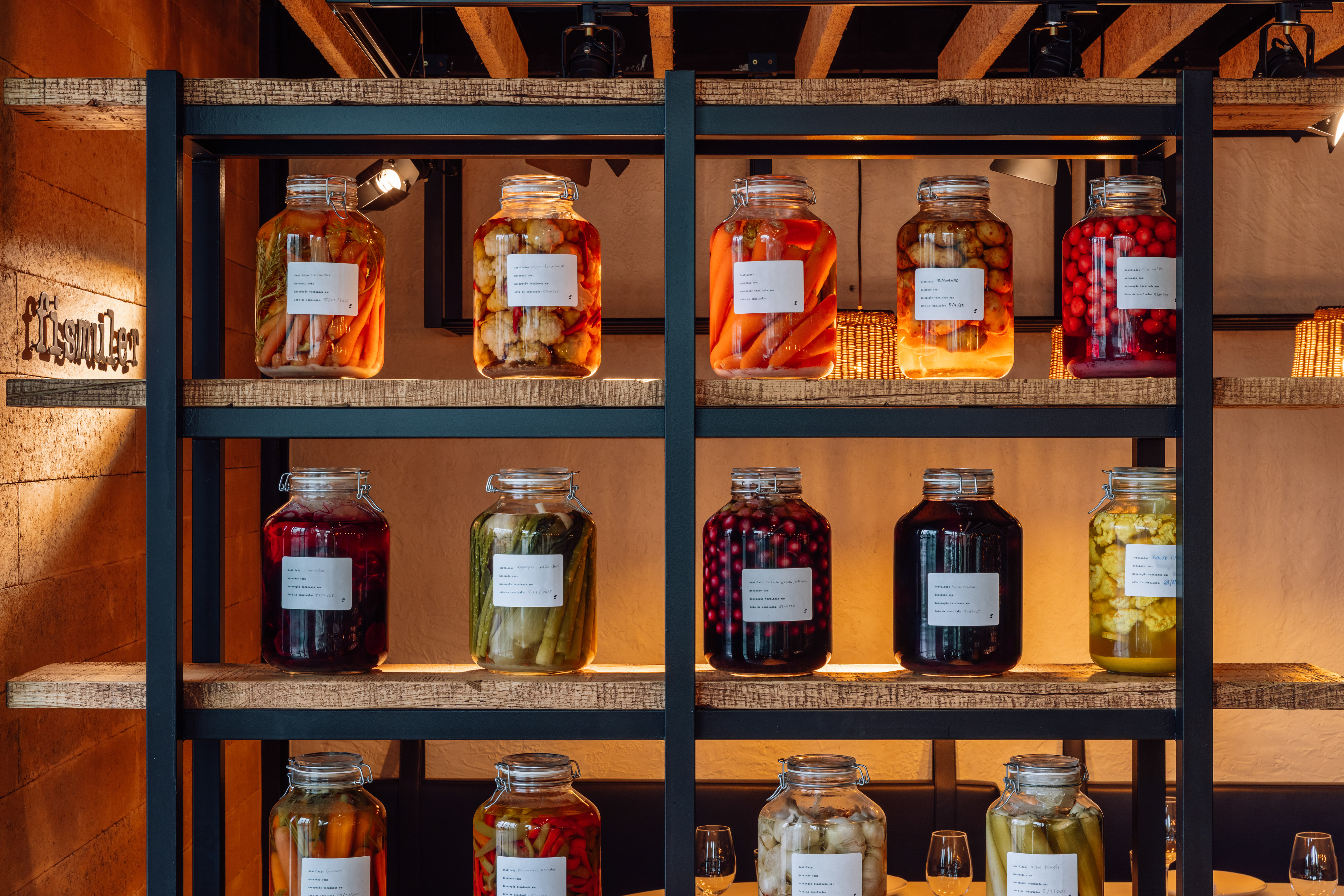 Rustic shelves displaying gourmet pickled vegetables in glass jars.