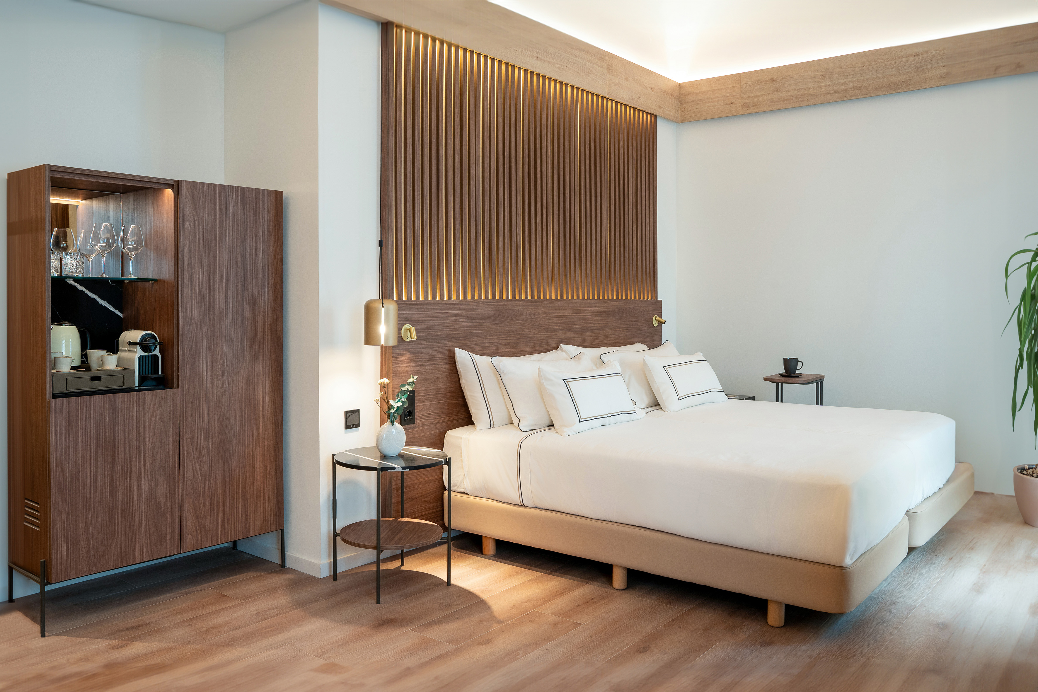 Luxury hotel room with wood slatted headboard, minibar, and king bed.