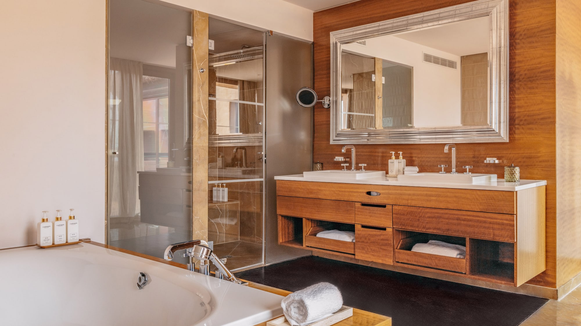Modern luxury bathroom with bathtub, double vanity, wood accents, and glass shower.