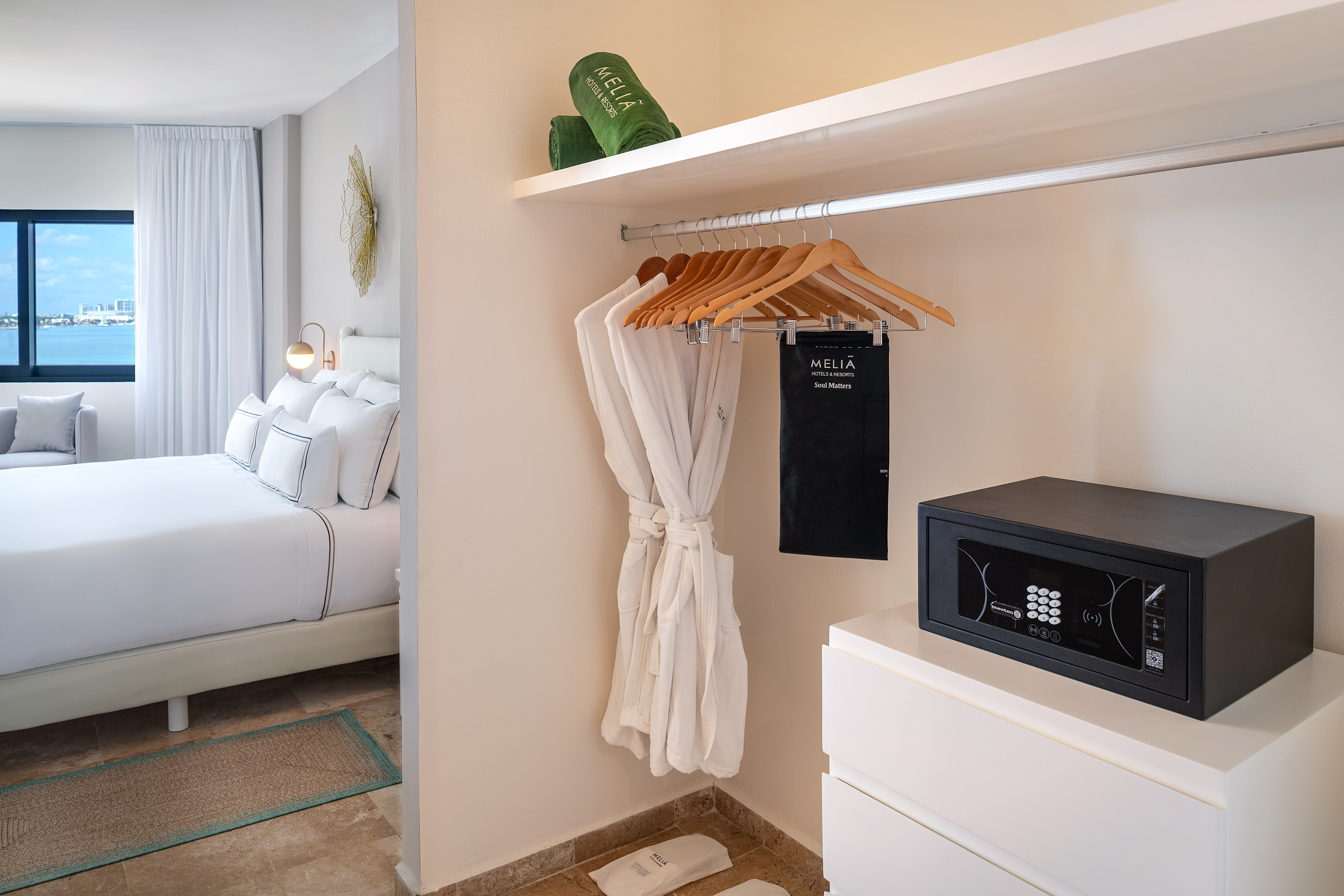 Melia hotel room amenities: open closet with robes, safe, bed, ocean view.