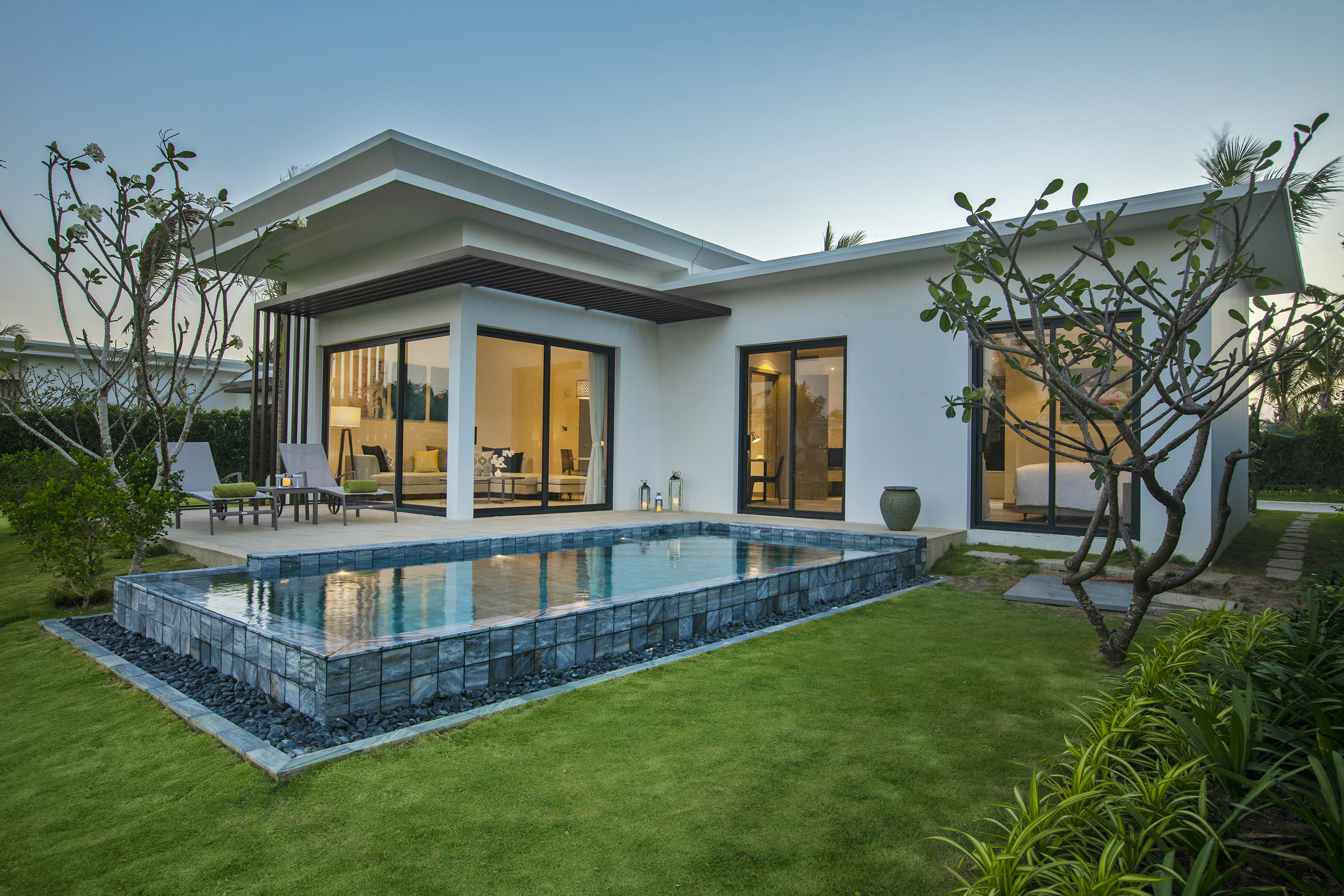 Modern white villa with private pool, outdoor lounge, and tropical garden.