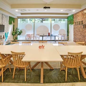 a room with white tables and wooden chairs
