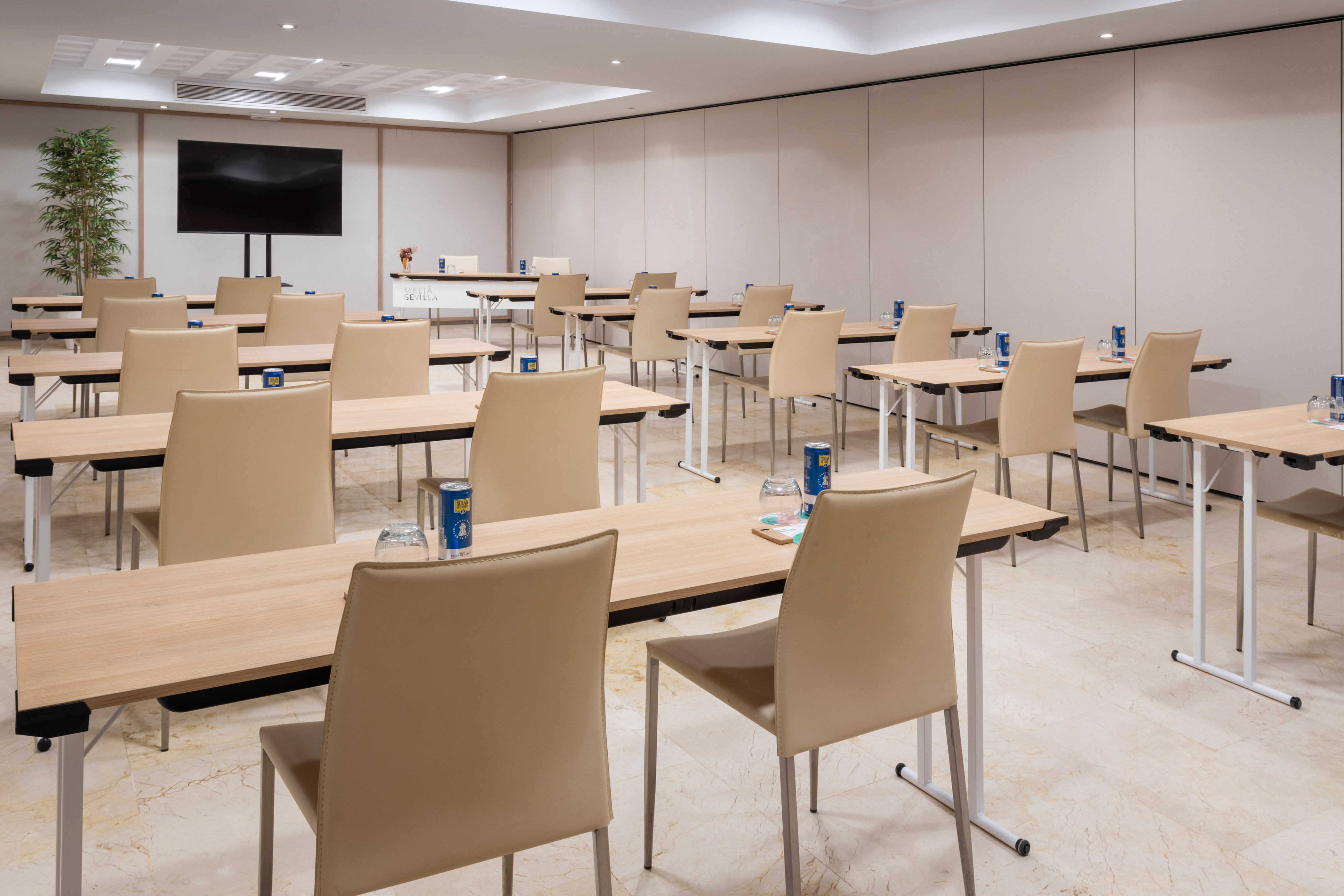 Modern meeting room with classroom setup, tables, chairs, and large screen.