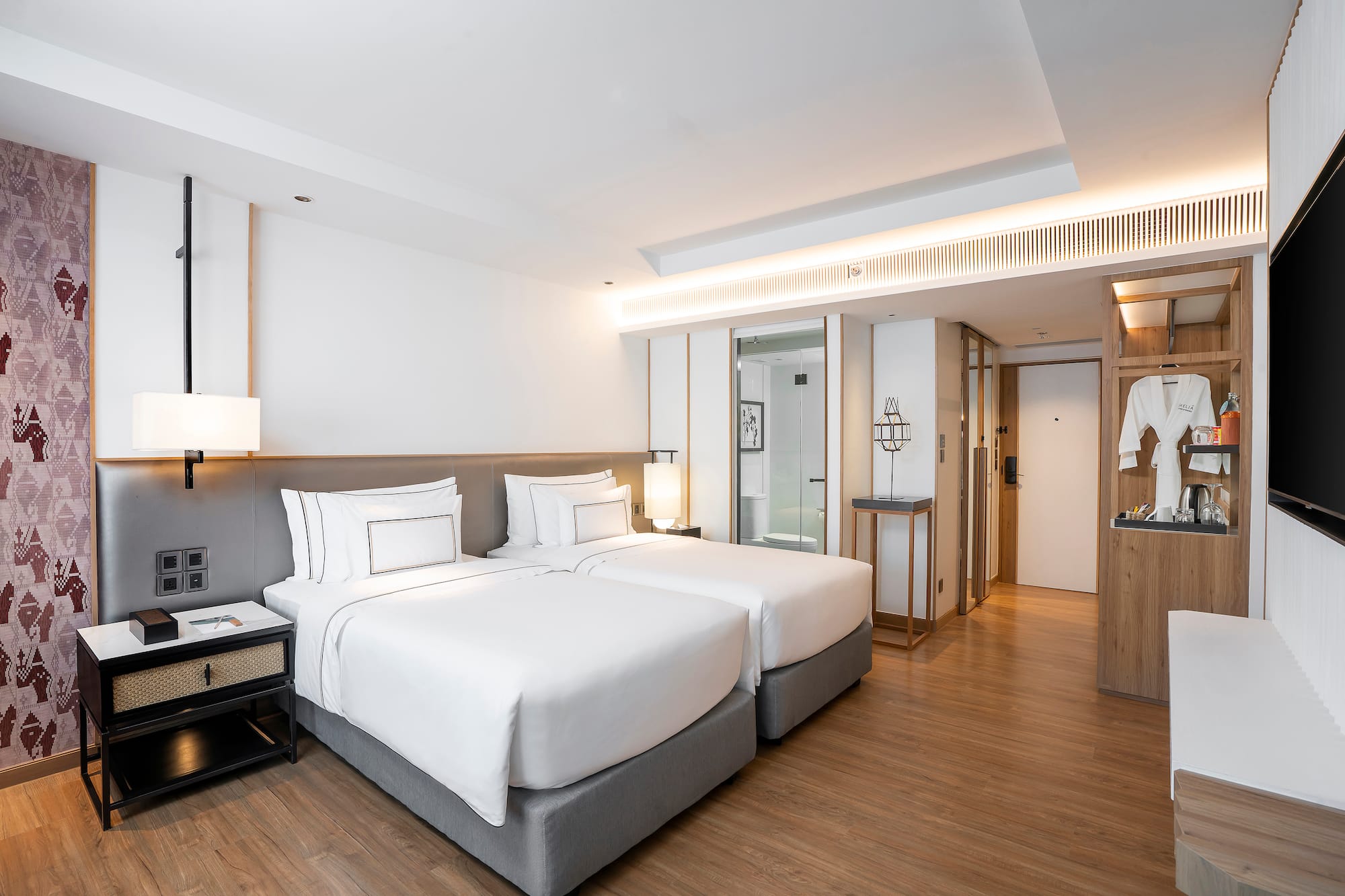 Contemporary hotel room with two twin beds, hardwood floor, and modern decor.