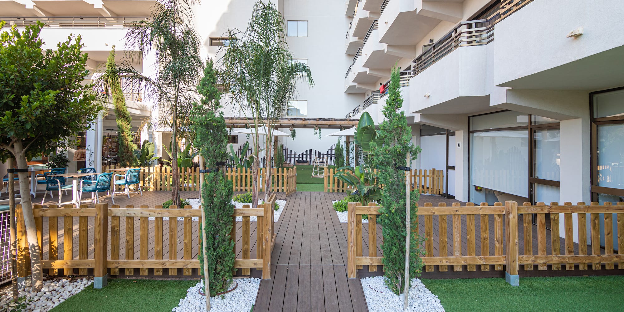 a wooden walkway in a courtyard with trees and a wood walkway