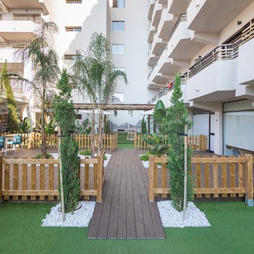 a wooden walkway in a courtyard with trees and a wood walkway