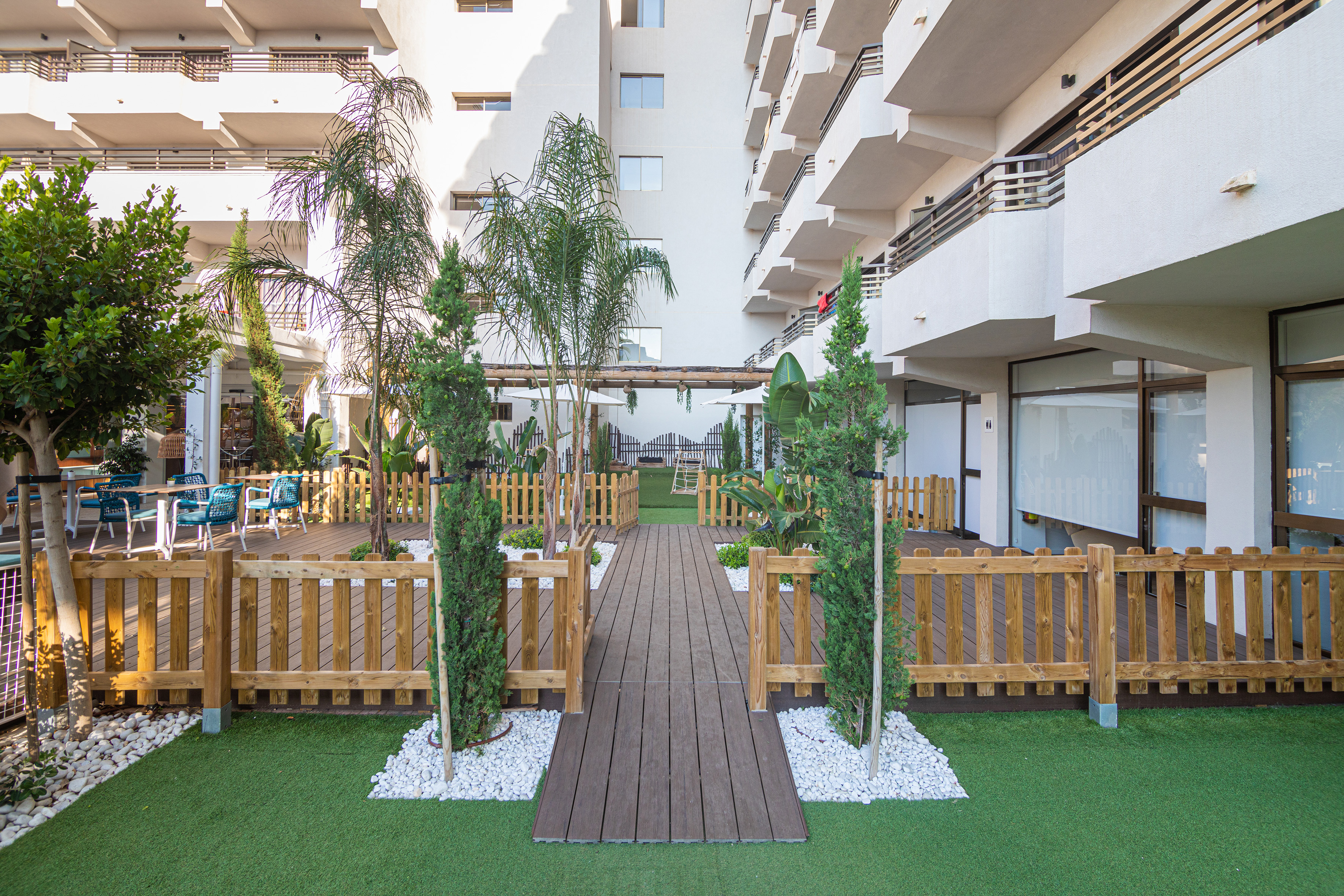 a wooden walkway in a courtyard with trees and a wood walkway