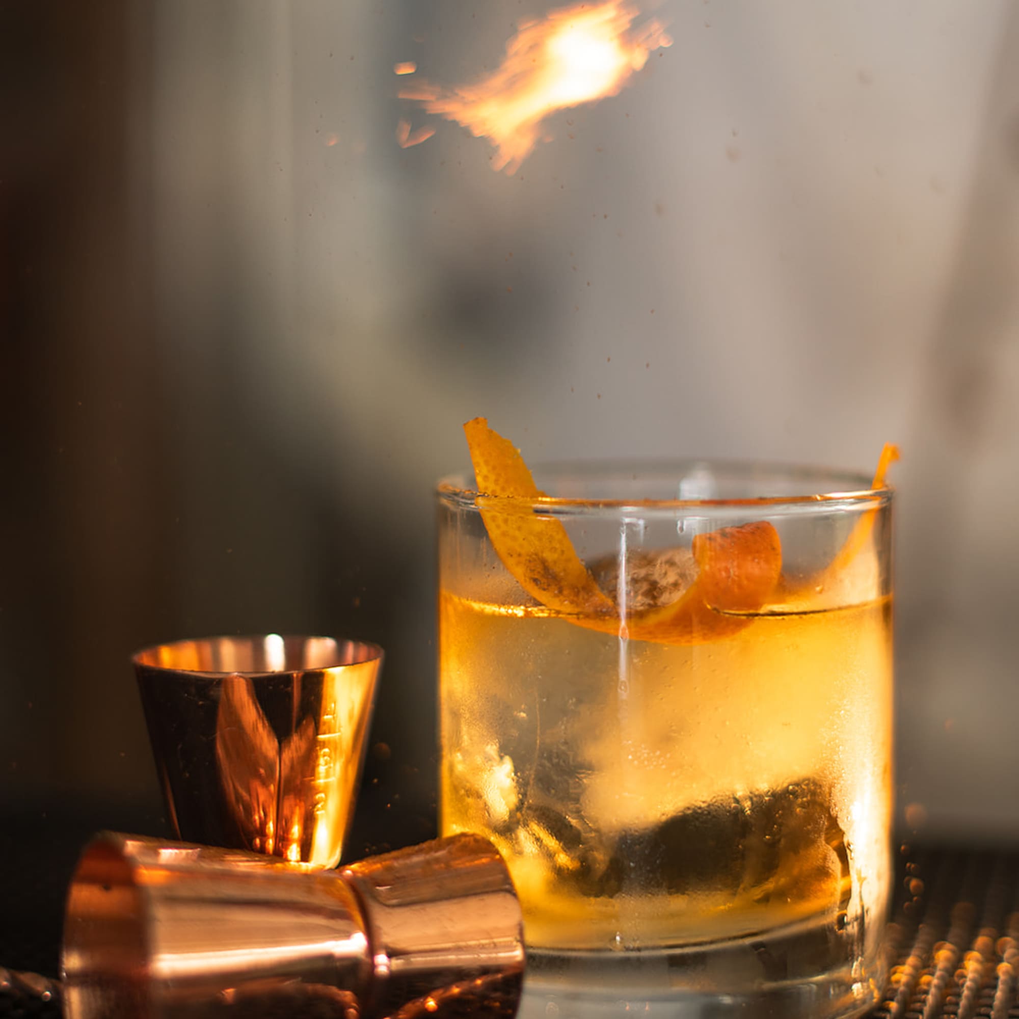 a glass with a drink and a fire above it