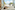Woman in bed, family on balcony overlooking beach and palm trees.