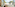 Woman in bed, family on balcony overlooking beach and palm trees.