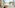 Woman in bed, family on balcony overlooking beach and palm trees.