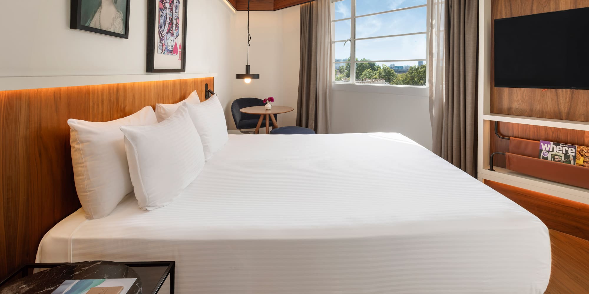 Bright modern hotel room with king bed, window view, and contemporary decor.