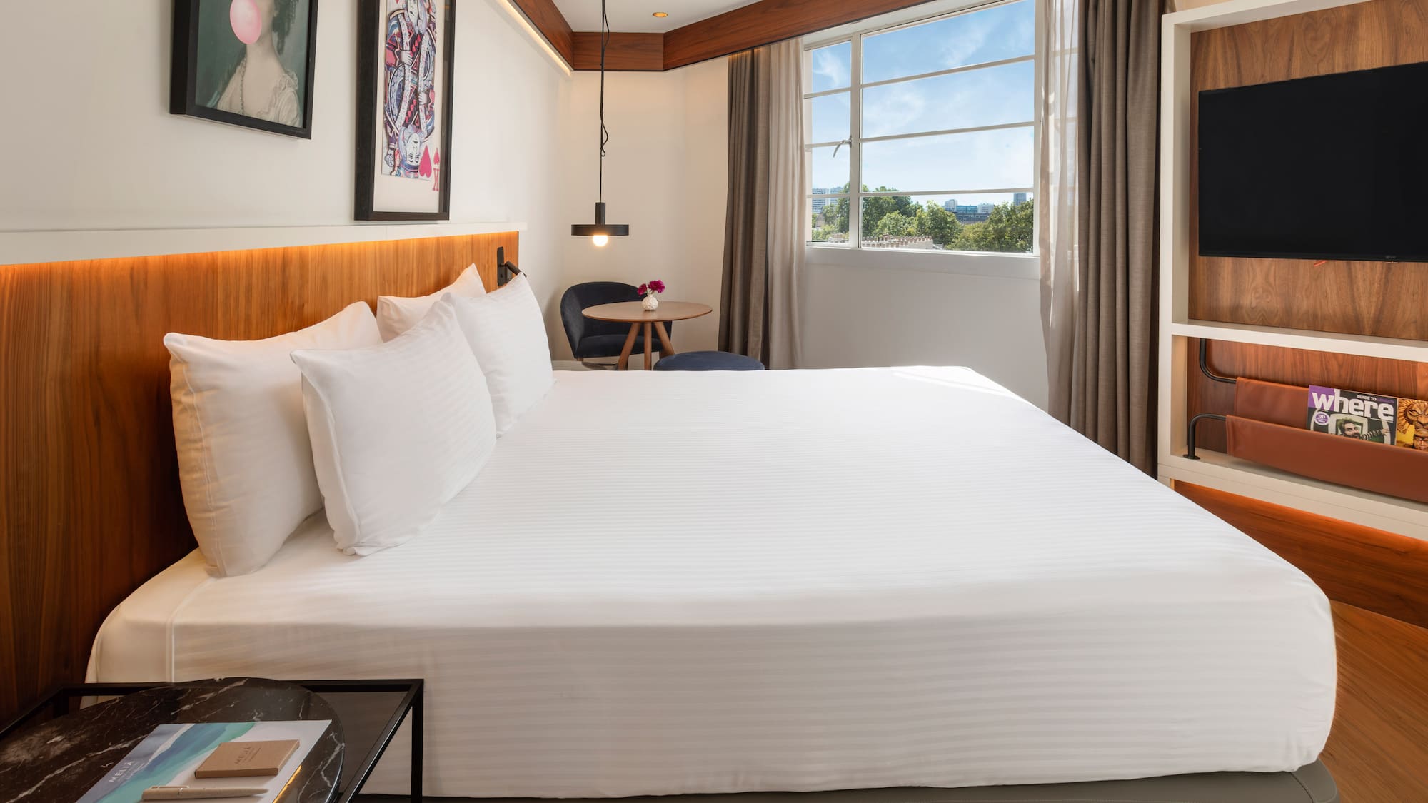 Bright modern hotel room with king bed, window view, and contemporary decor.