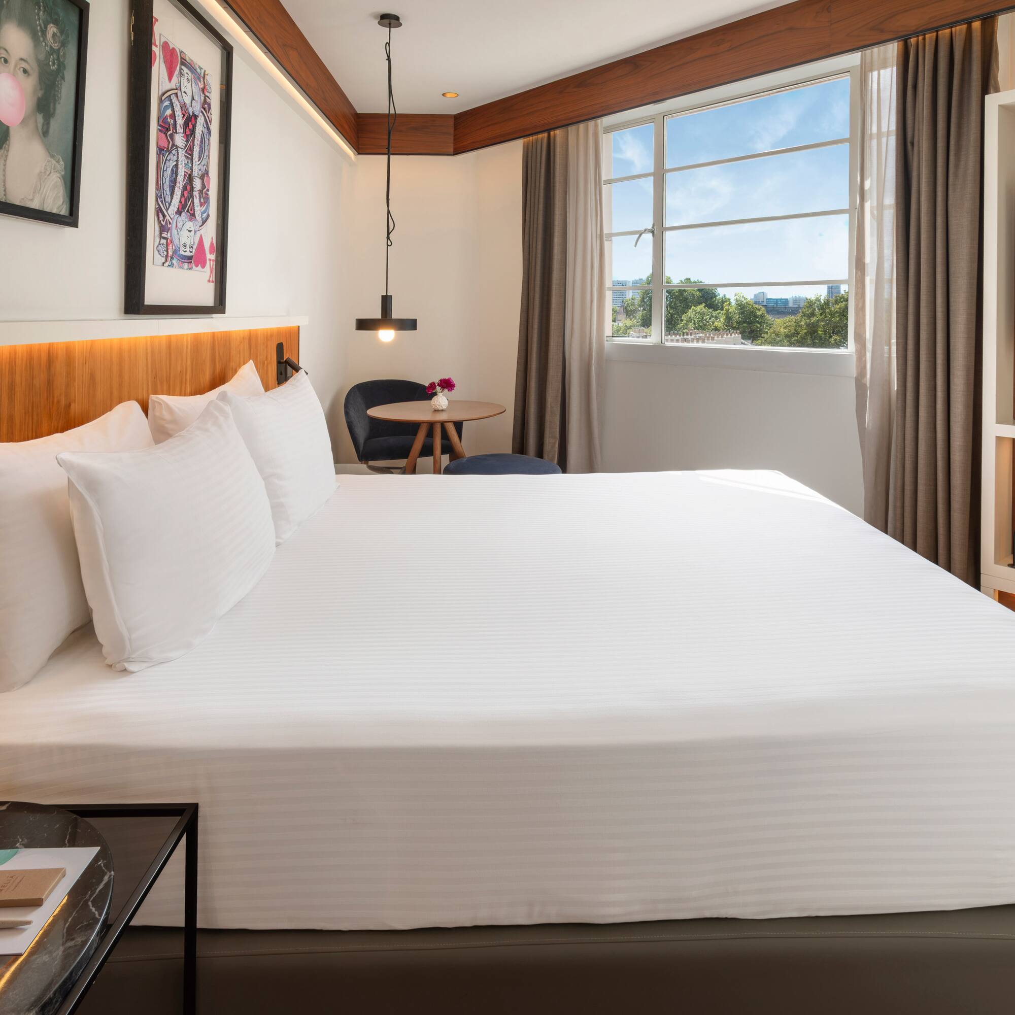 Bright modern hotel room with king bed, window view, and contemporary decor.