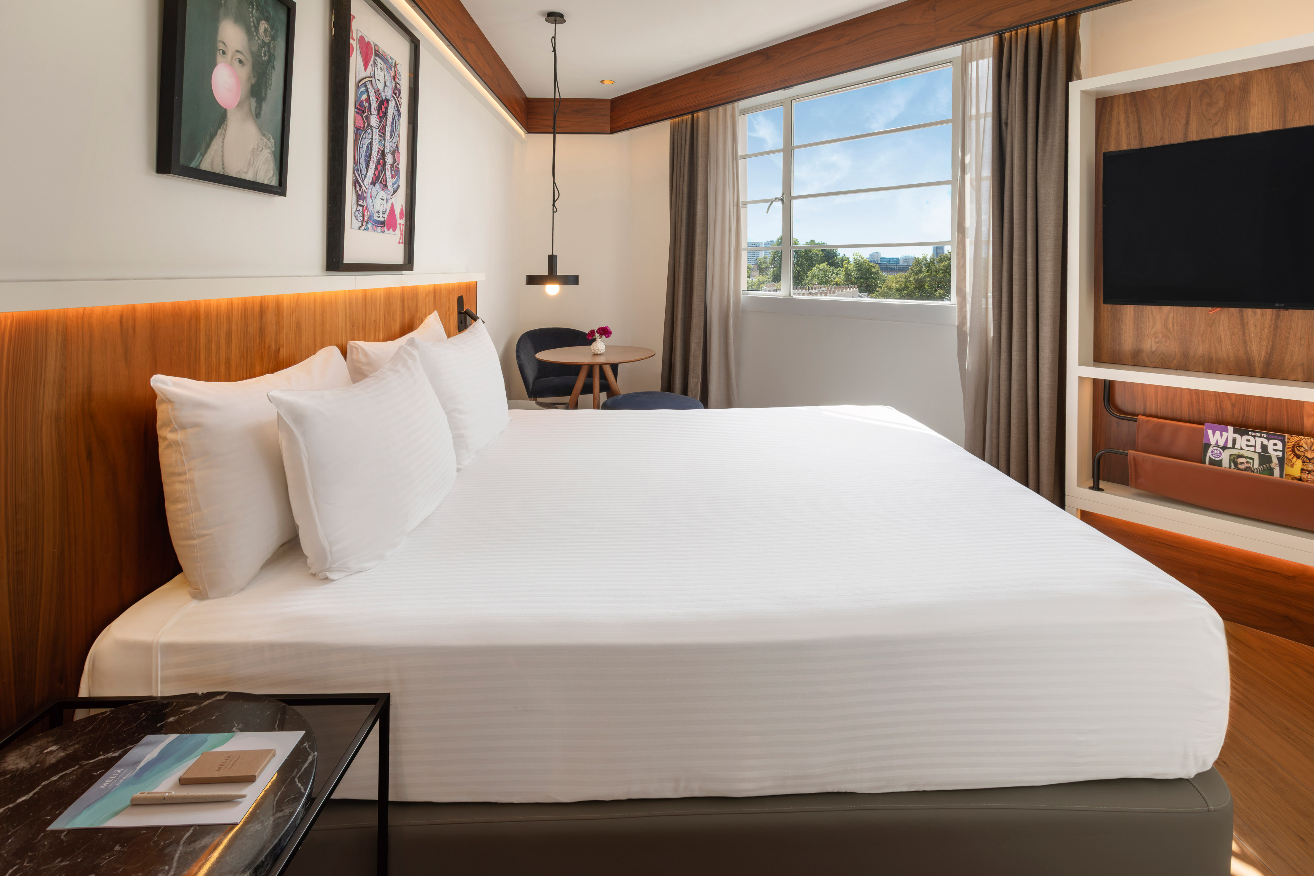 Bright modern hotel room with king bed, window view, and contemporary decor.