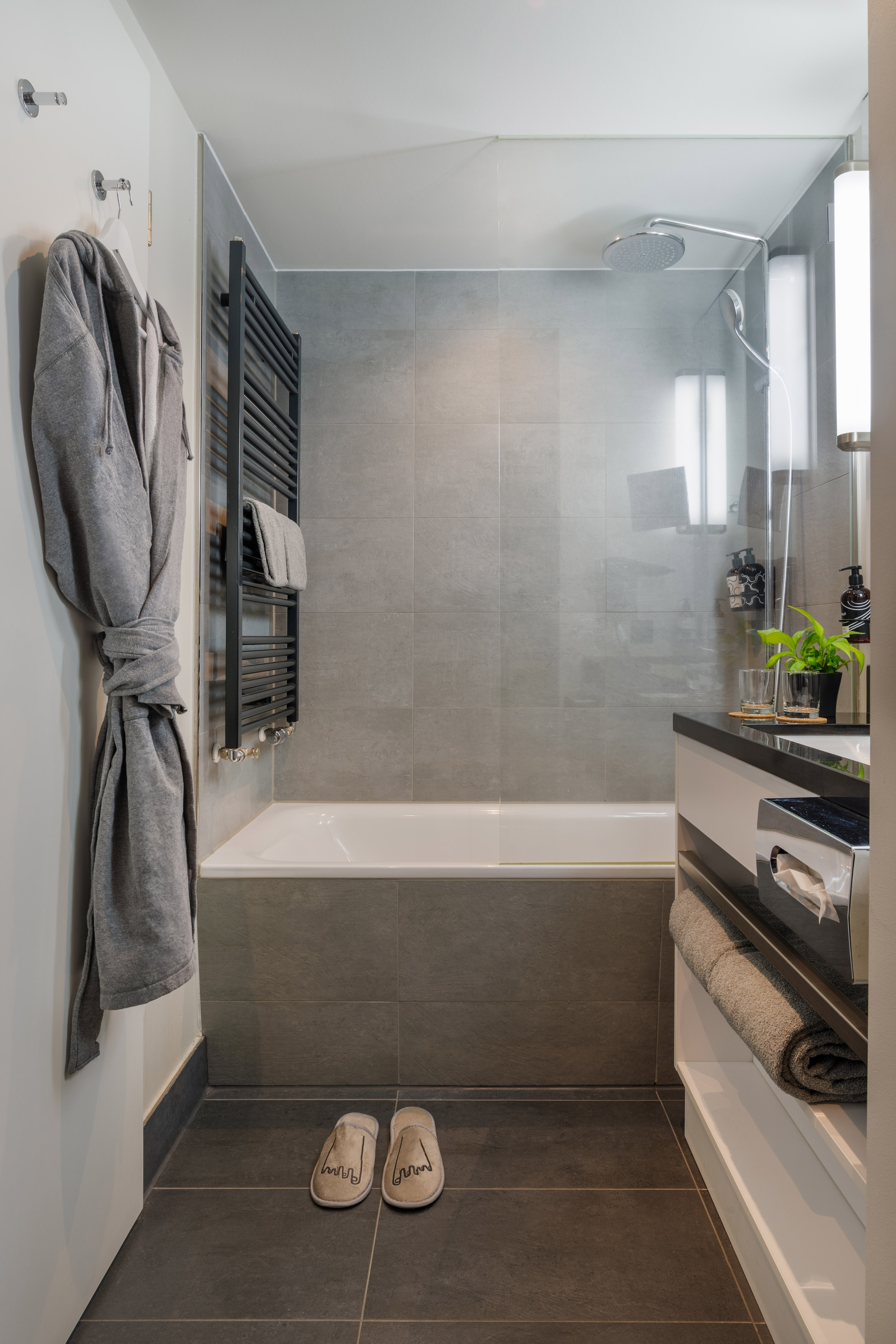 Modern gray bathroom, bathtub, shower, black towel radiator, bathrobe.
