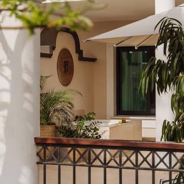 a white building with a white umbrella and plants