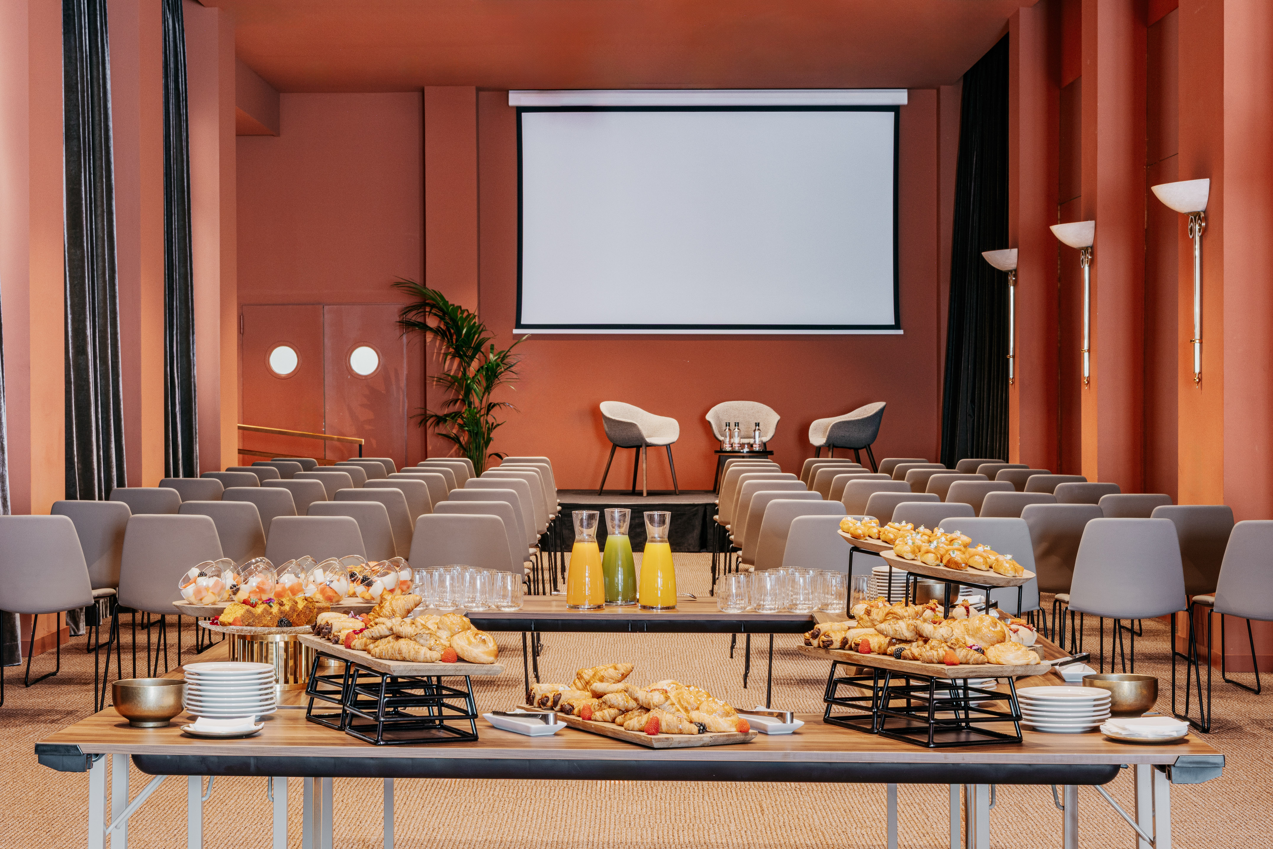 Event space with projection screen, rows of chairs, and breakfast buffet.
